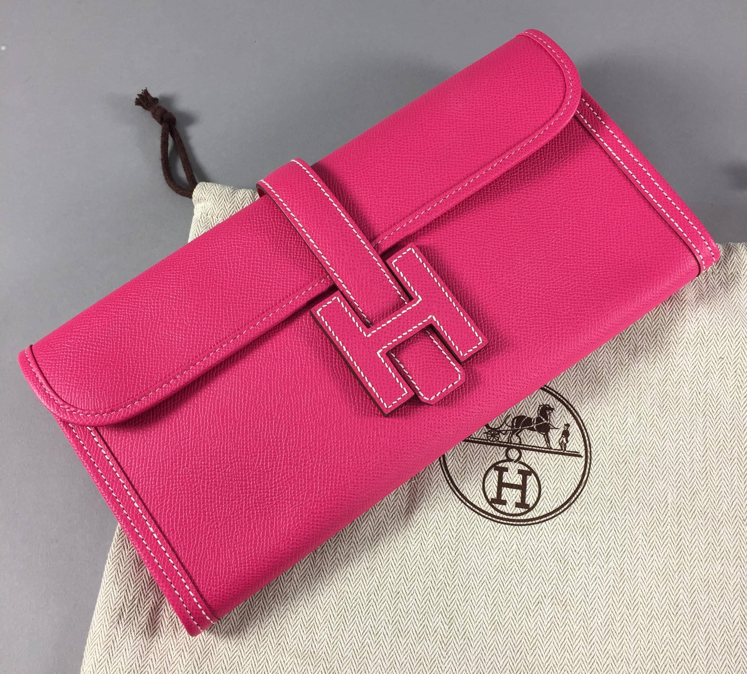 Hermes bright fuchsia pink Jige clutch. Excellent unused condition with original duster. Date stamp 2012. Measures 29cm long. 

We ship worldwide.  Canadian residents pay sales tax based on destination province.