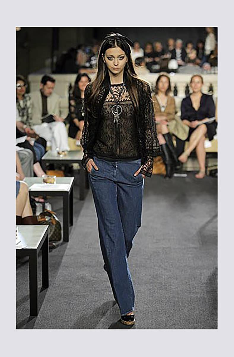 Chanel 2007 Cruise runway collection black lace shirt. Buttons up at back with black enamel CC logo buttons, has ribbon that can be tied into a bow at centre front, long sleeves with ruched wrists and split cuffs. Excellent pre-owned condition.