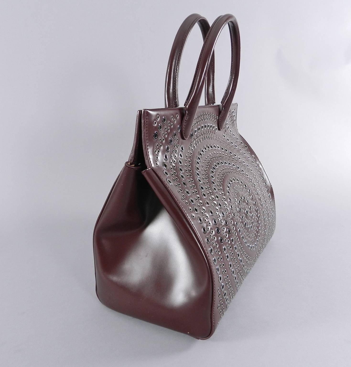 Alaia burgundy leather doctor tote bag with grommet detail on front and back. Excellent pre-owned condition with no wear – used once if at all. Comes with interior zip coin pouch and mirror. Original retail price tag of $3280+ is included. Body of