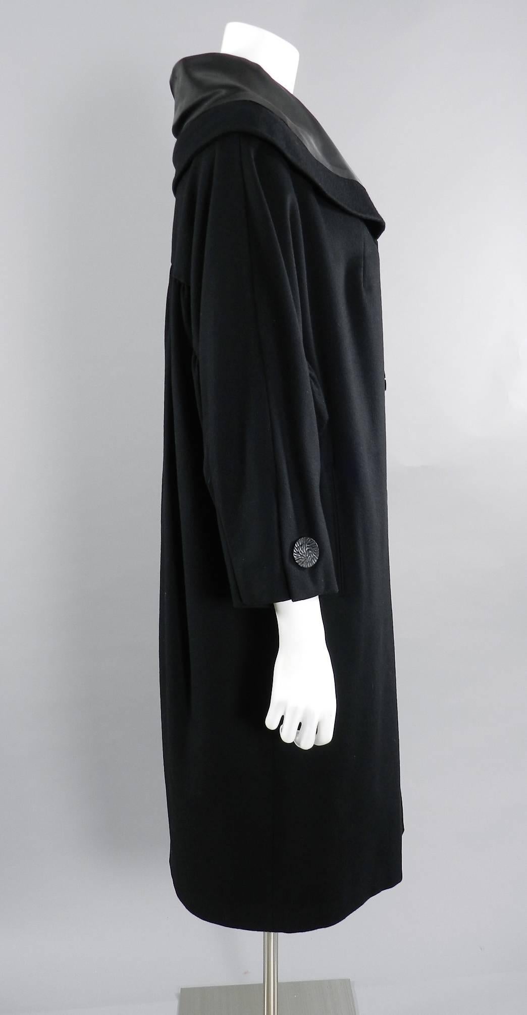 Vintage 1950's Norman Hartnell black wool coat. Wide satin faced collar, plastic buttons, side hip pockets. Rushed design at sleeves and back.  Overall size S/M (about USA 6-8). Garment measures 48" across bust and 48" across hip and is