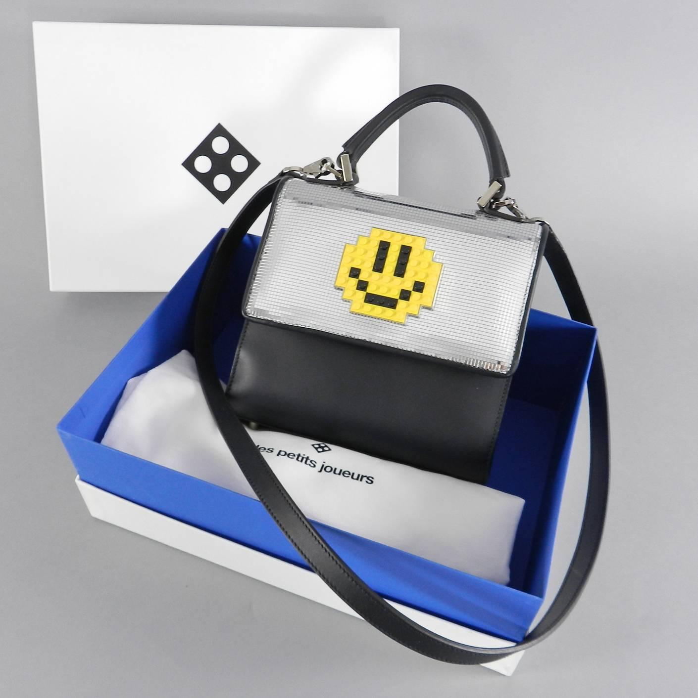 Les Petit Joueurs Mini Alex Smile Bag. Black leather body with silver metallic front and yellow real lego smiley face.  Like new - used once - excellent clean condition with original box and papers.  Body of bag measures 8 x 7.5 x 3.5