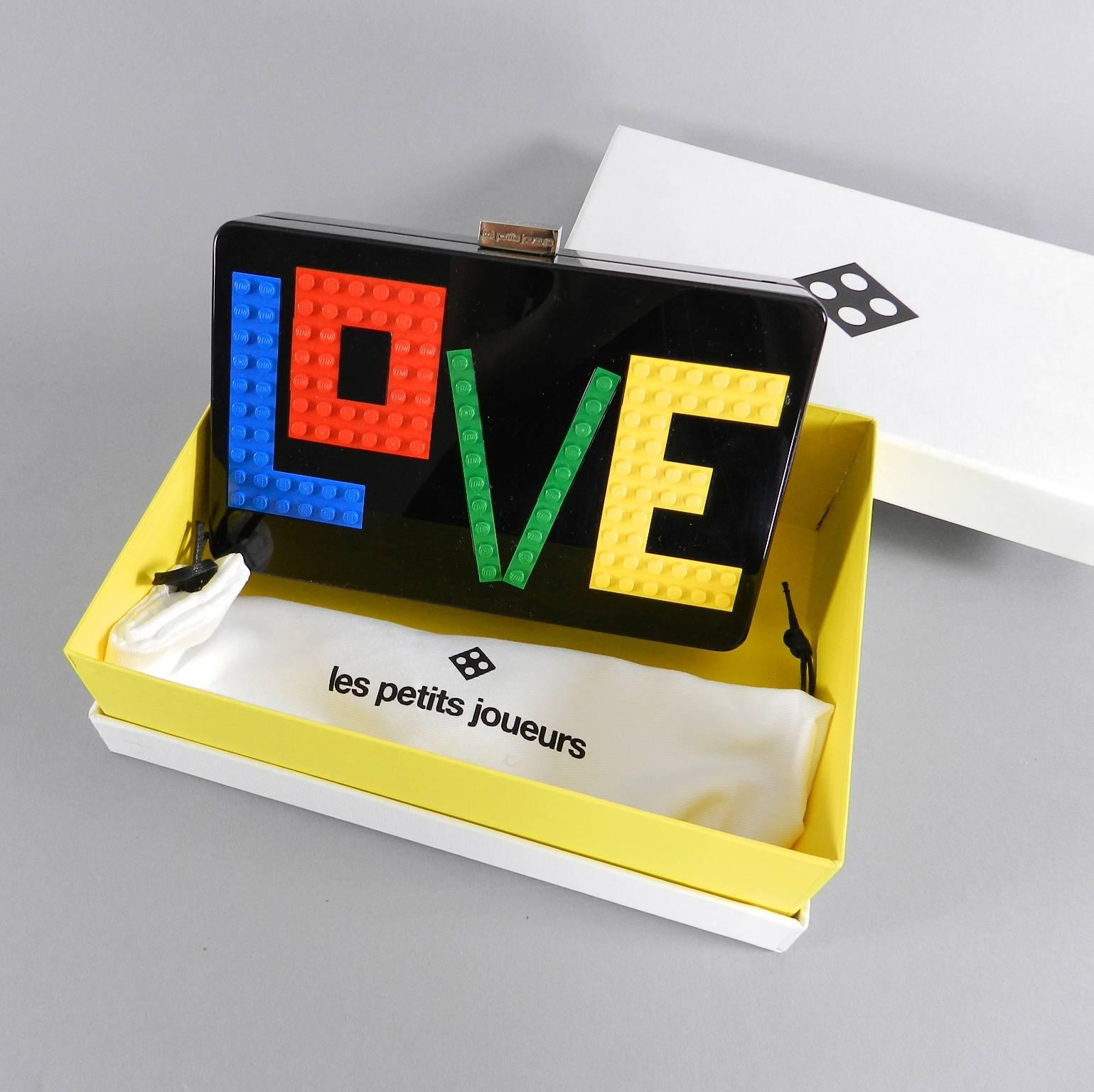 Les Petit Joueurs Andy rainbow love clutch. Black acrylic plastic body with multicolor LEGO detail.  Unused with original purchase receipt, box and papers.  Body of bag measures 7.5 x 4.5 x 1.75