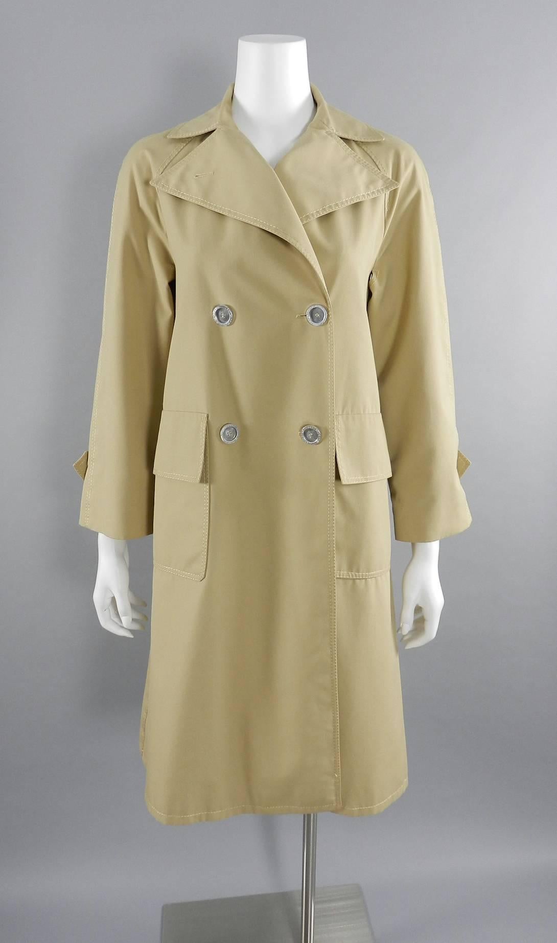 Vintage 1970's Hermes Sport trench coat. Label reads Hermes Sport for Bonwit Teller. Beige cotton spring light trench coat with sash belt and aluminum metal logo buttons. Size USA small - 4. Garment bust measures 36