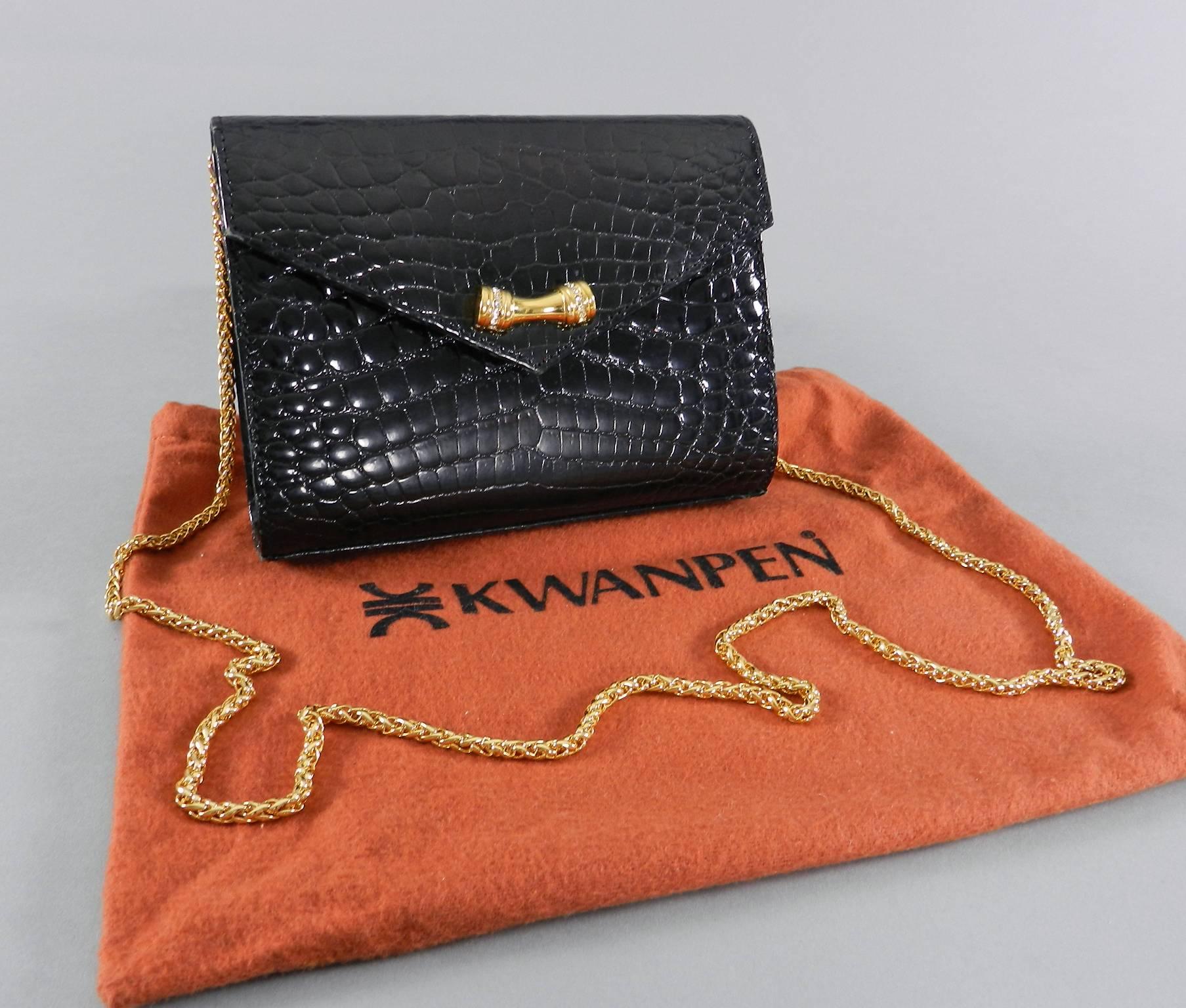 Kwanpen small black crocodile evening bag.  From Singapore based luxury bag label specializing in crocodile bags since 1938. Goldtone metal bow detail and chain strap that can be tucked inside when worn as clutch. Bag measures 6.75 x 5 x 1.75