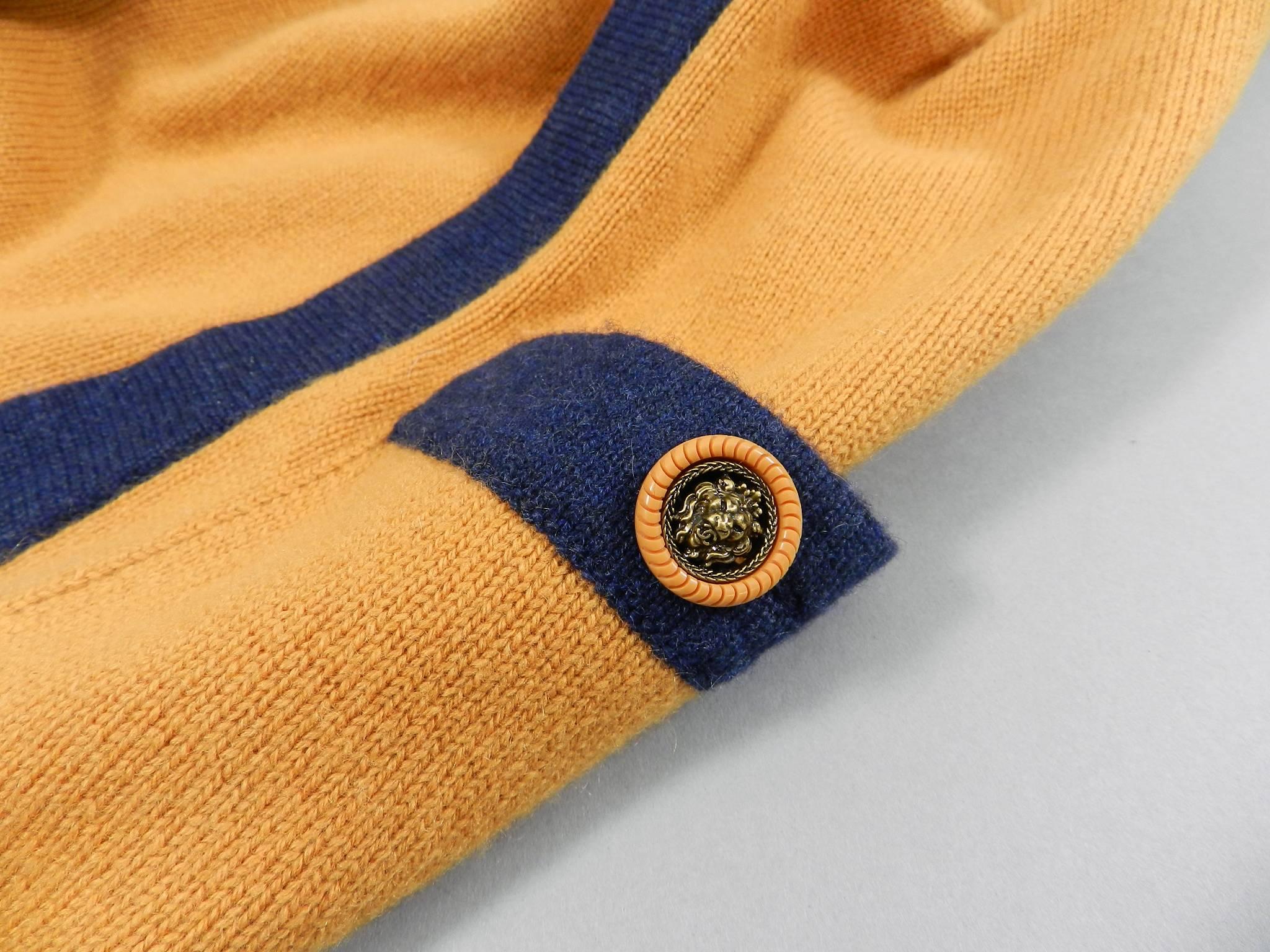 Chanel mustard and navy V-neck Cashmere sweater.  Lion head buttons.  Tagged size FR 38 (usa 6) but fits oversized and can fit larger. Garment bust measures 44" unstretched when laid flat, garment hip is 40" unstretched. Shoulder seams