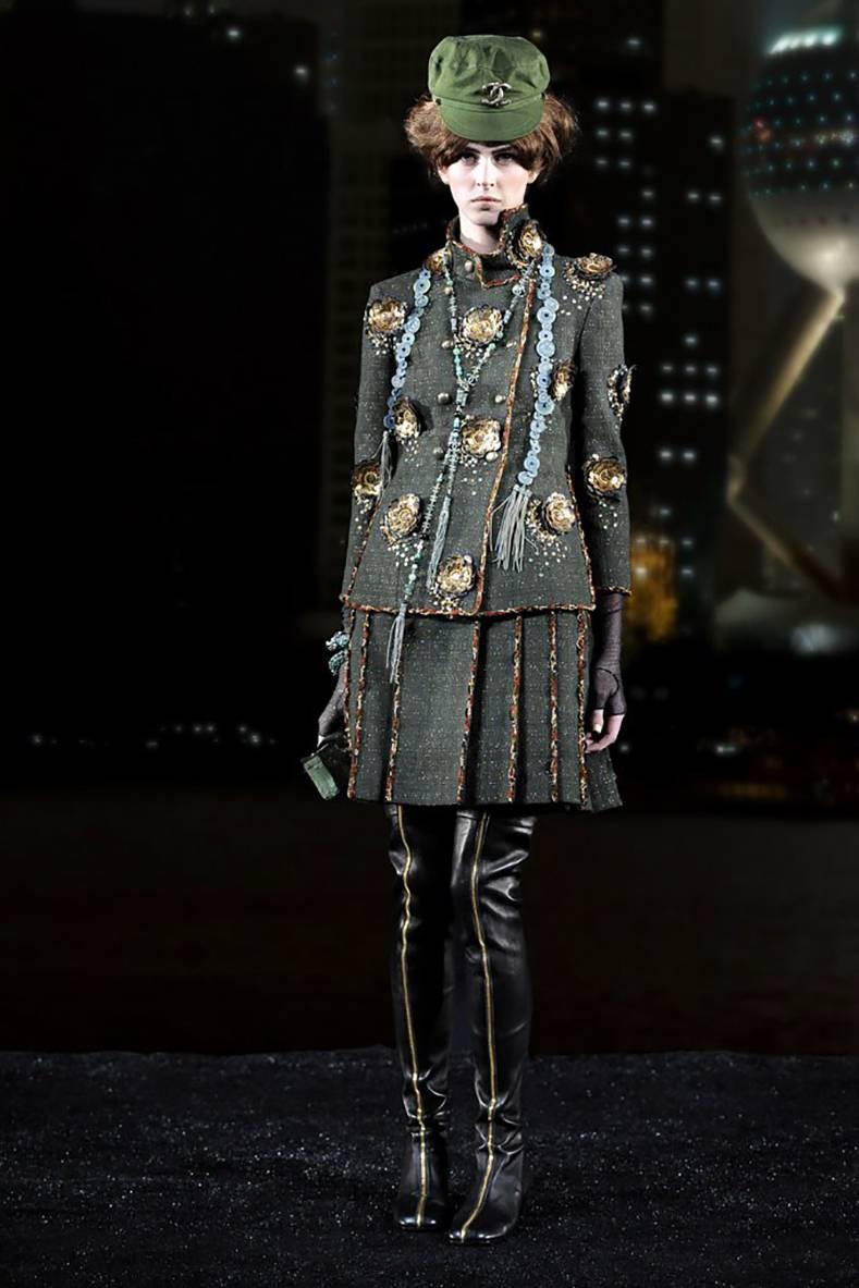 Chanel Pre-Fall 2010 Shanghai Runway Green skirt Suit with Gold Lesage Camelias.  Stand up collar, double row of olive enamelled buttons, lesage tweed trim, gold leather and sequin camelia detail, bracelet length sleeves, side slits at jacket sides.