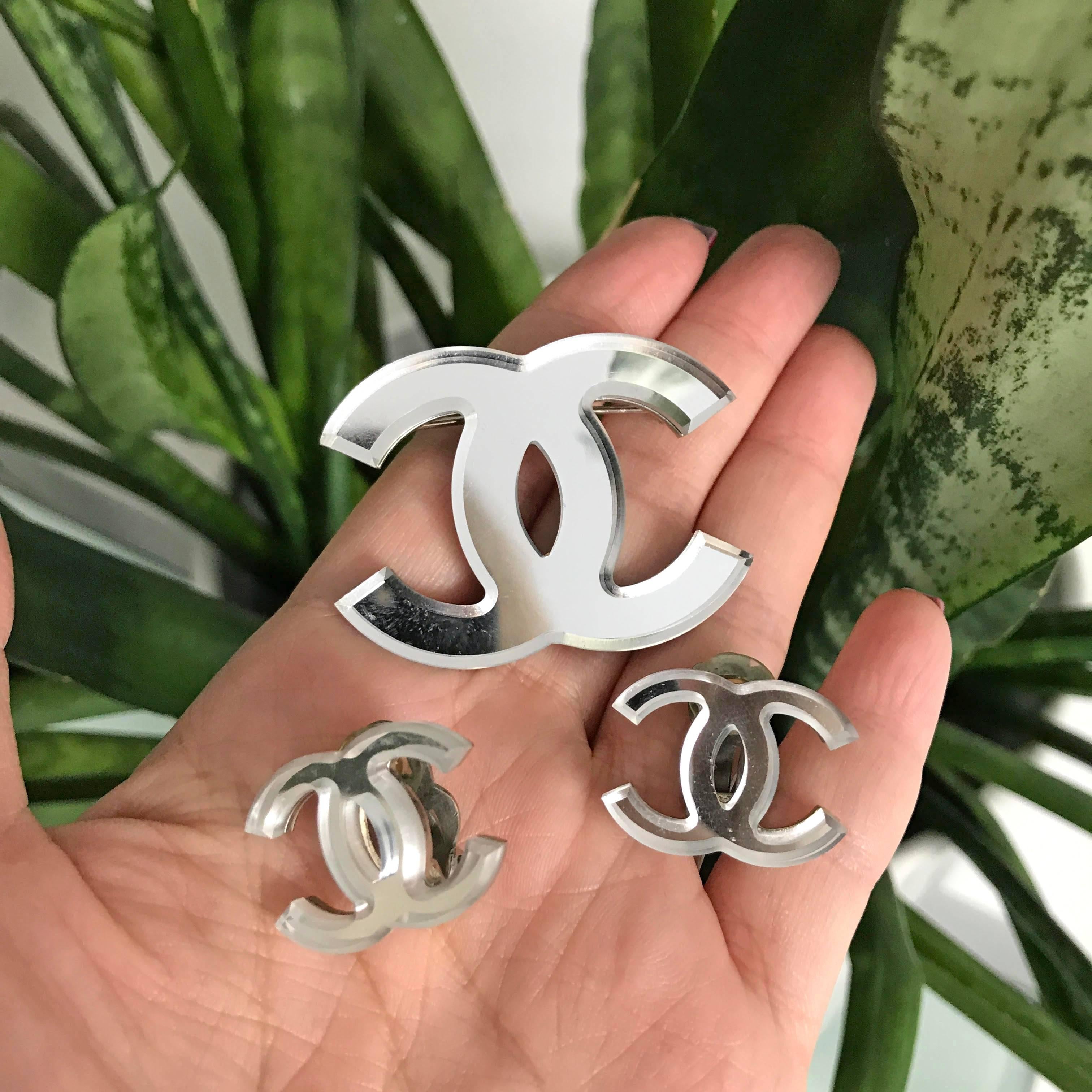 Chanel 03A glass mirror CC logo brooch pin and clip earrings set. Silvertone metal back.  Earrings measure about 1" x 0.75" and pin measures about 1.75" x 1-3/8".  Excellent pre-owned.

We ship worldwide.