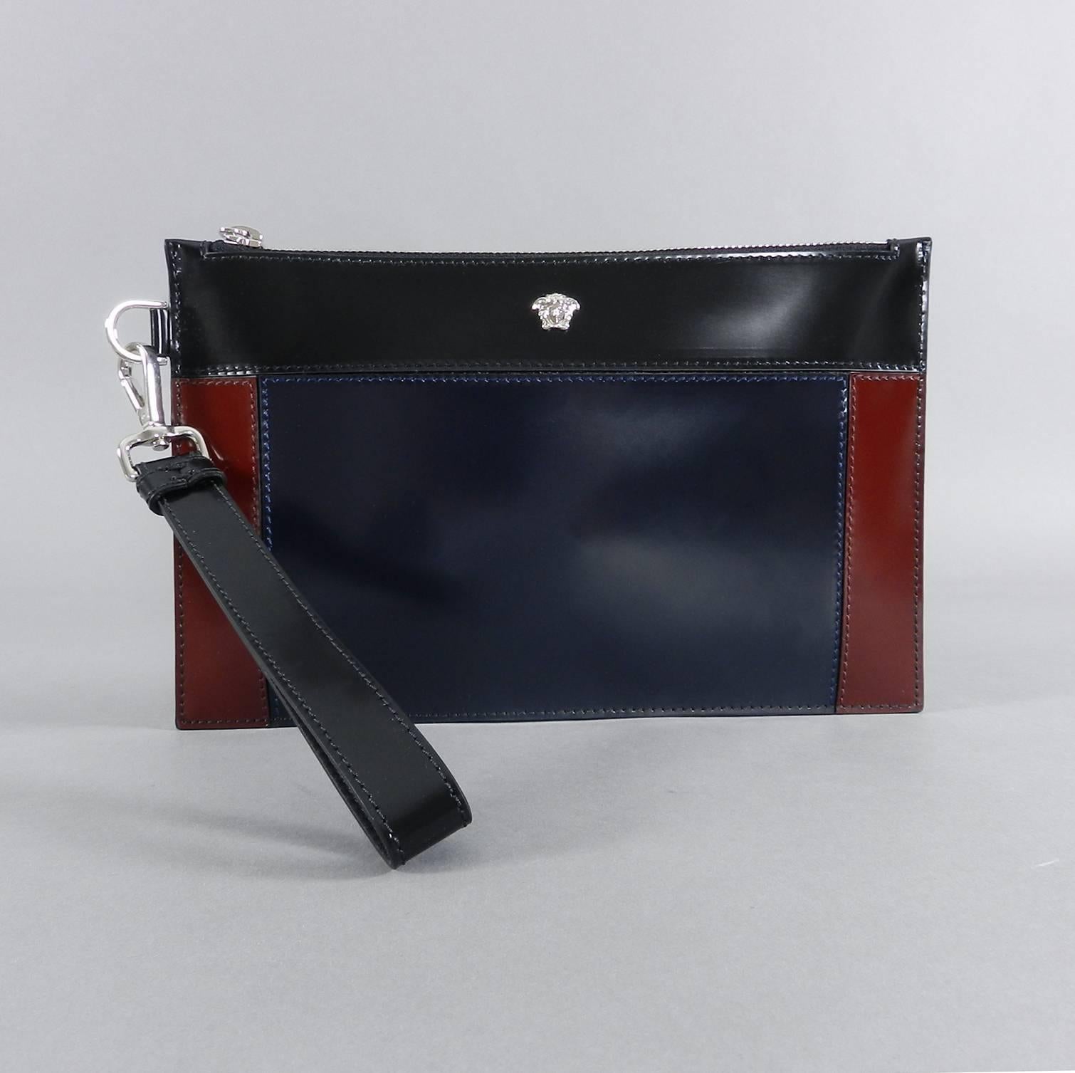 Versace Navy, Burgundy, Black Colorblock Leather Wristlet Clutch Bag.  Removable wrist strap, silvertone metal hardware, signature medusa head stud at front.  Includes duster.  Fabric lined, glossy high shine leather, color block design.  New