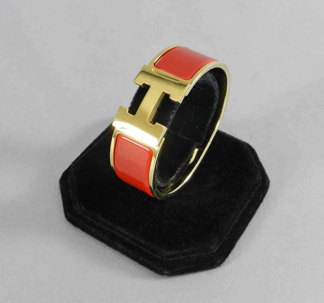 Hermes goldtone clic clac bracelet with H clasp in poppy / tomato red color.  PM size (Hermes says this should fit a wrist size of 15.5cm or 6 inches).  The interior circumference of the bracelet measure 6.25".  Total width is 20mm.  Excellent