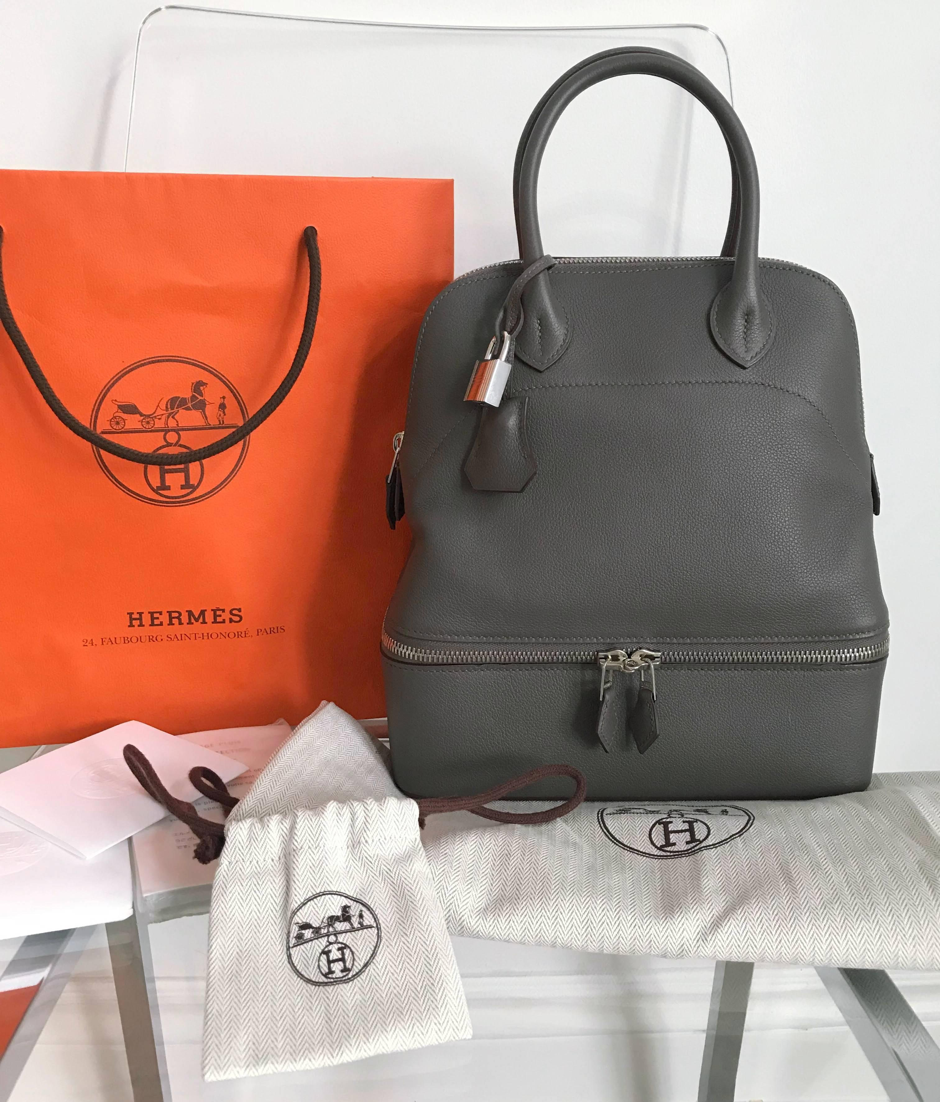 Hermes Bolide Secret bag with double zippered bottom compartment.  PM small size measuring 24 x 27 x 10cm. Smooth Veau Evercolor leather, Etain color, and palladium hardware.  Double handle design with top zipper, two flat interior pockets, and
