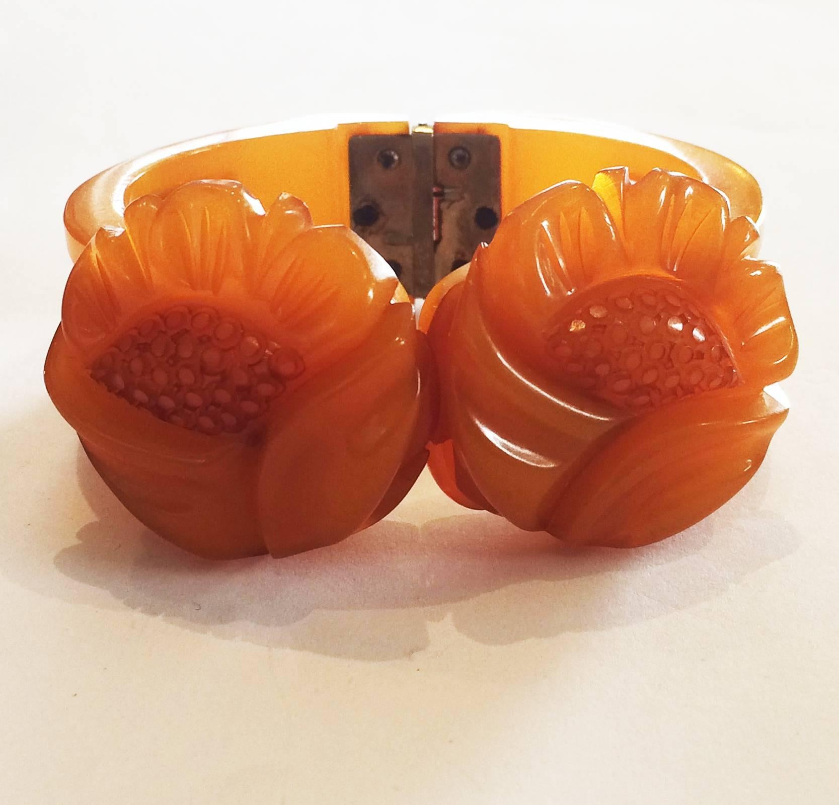 Art Deco Clamper, deeply Carved Bakelite Bangle in a Honeyed orange colour, with full depth, slotted band to each side, together with a large Daisy at each side of the opening. Each Daisy also rotates so the decoration can be changed at will. An