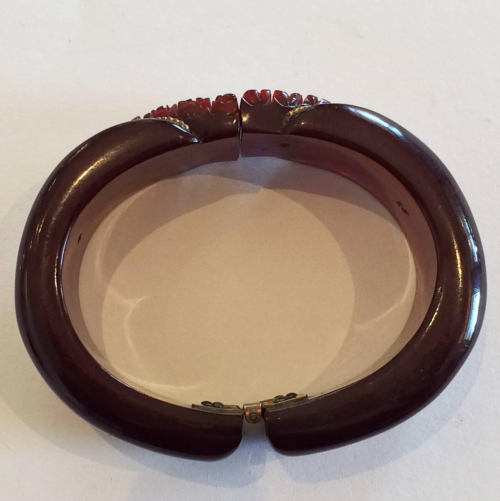 Art Deco Clamper Bangle in intricately carved, Deep Cherry Amber coloured Bakelite, with gilt brass, twisted “rope”, “V” inset to each carved side. Original spring hinge in perfect condition, with no damage or repairs at all to the bangle. One of