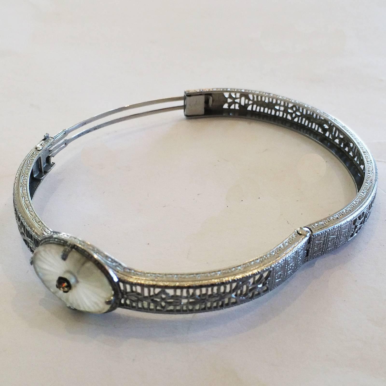 Art Deco Rhodium Bracelet in Filigree, set with carved Camphor Glass and central small Diamond. The bangle has an internal, double circular track that releases when the double safety clips are depressed, and the opposite side is hinged. All in