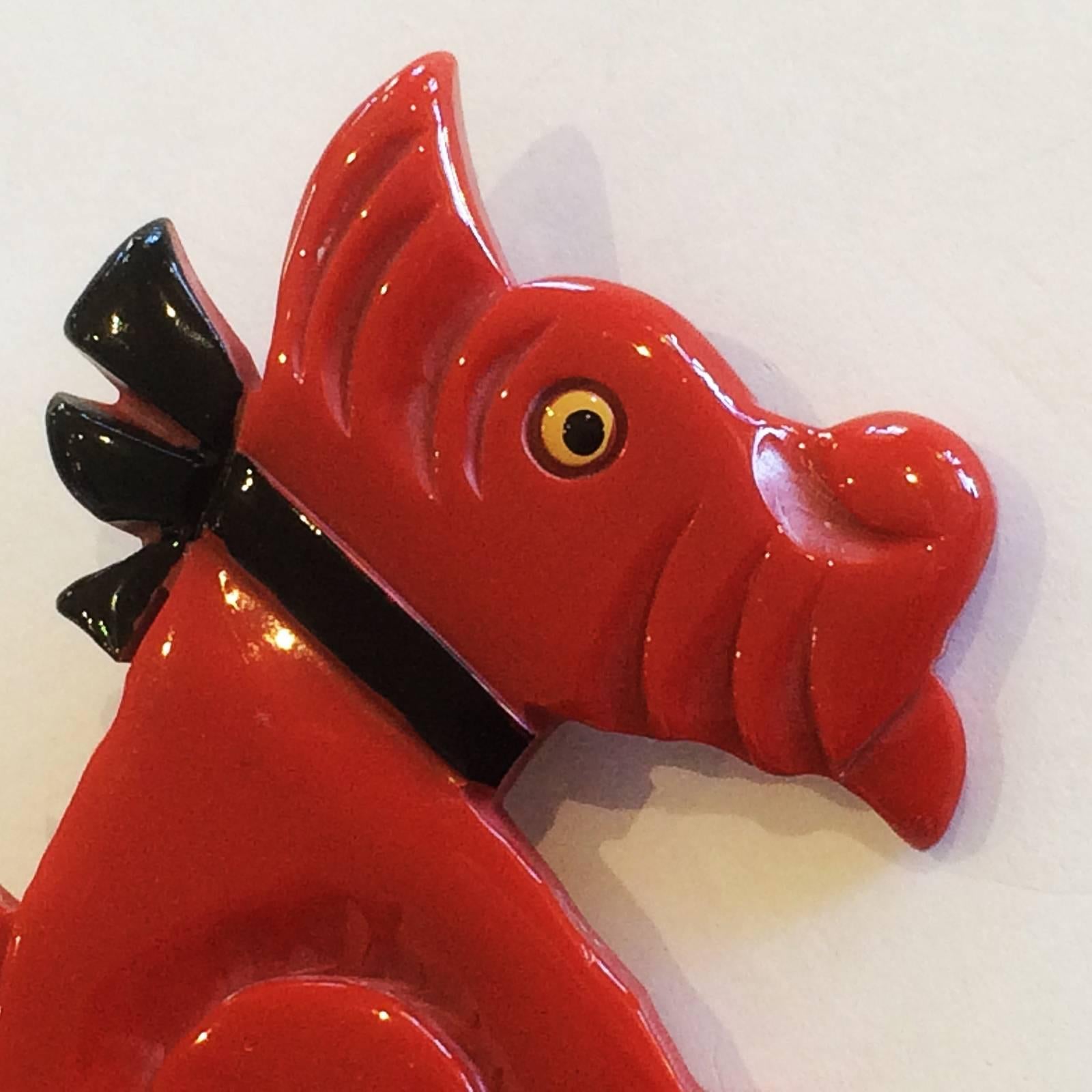 Art Deco Brooch in carved, Red Bakelite of a Scottie Dog, with fine coloured details to black Collar and eye. To the rear is the original, high quality, French safety catch, rivetted to the Bakelite, where, after you place the pin in the recess, the