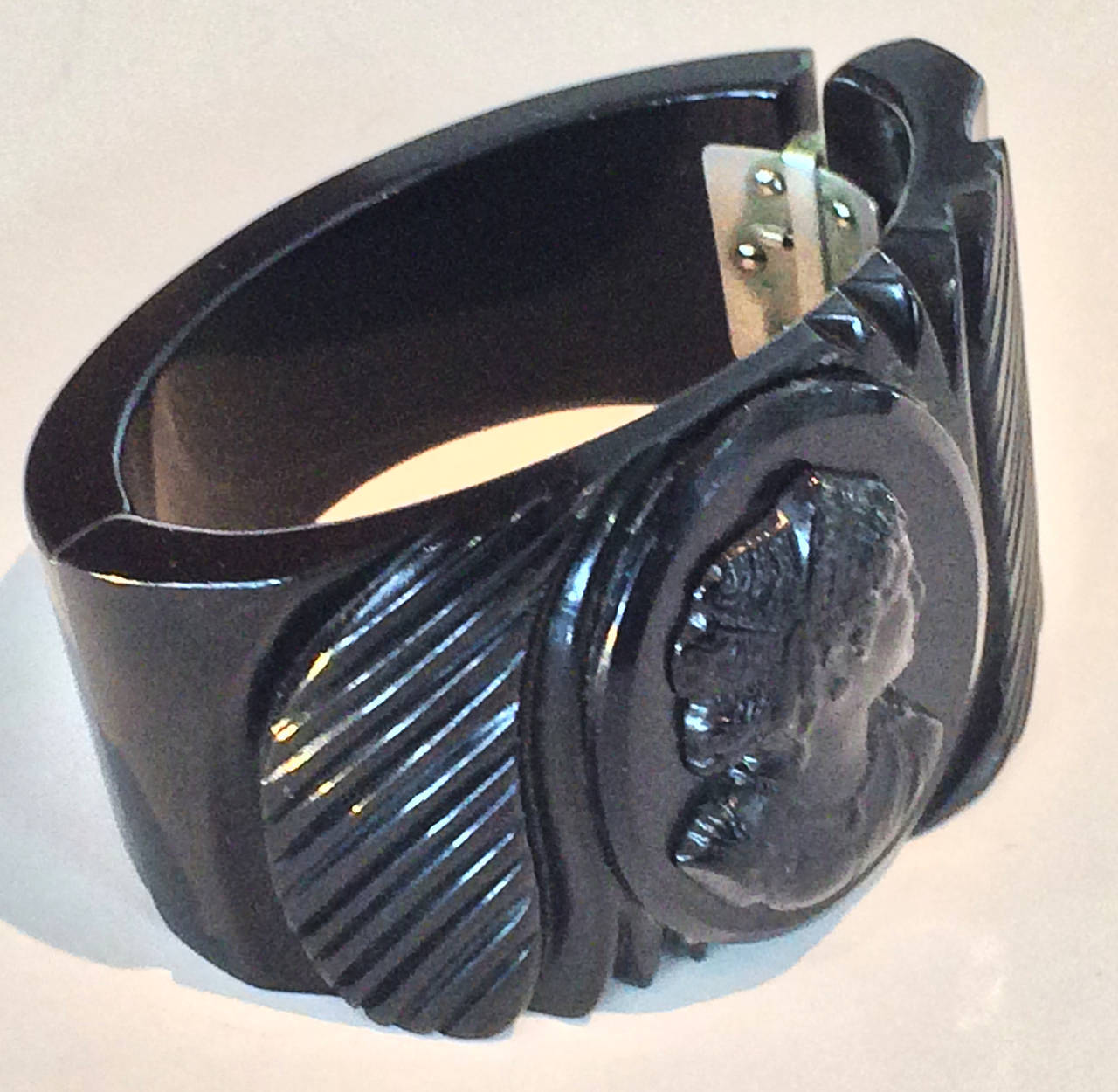 Art Deco Cameo Clamper Bangle in Black Bakelite, and perfect original nickel spring loaded hinge. All perfect, no repairs or damage, excellent age patina. Dimensions are approx..: Band oval interior 4.9cm x 6.1cm; wide varies 4.7cm at Cameo to 2.2cm