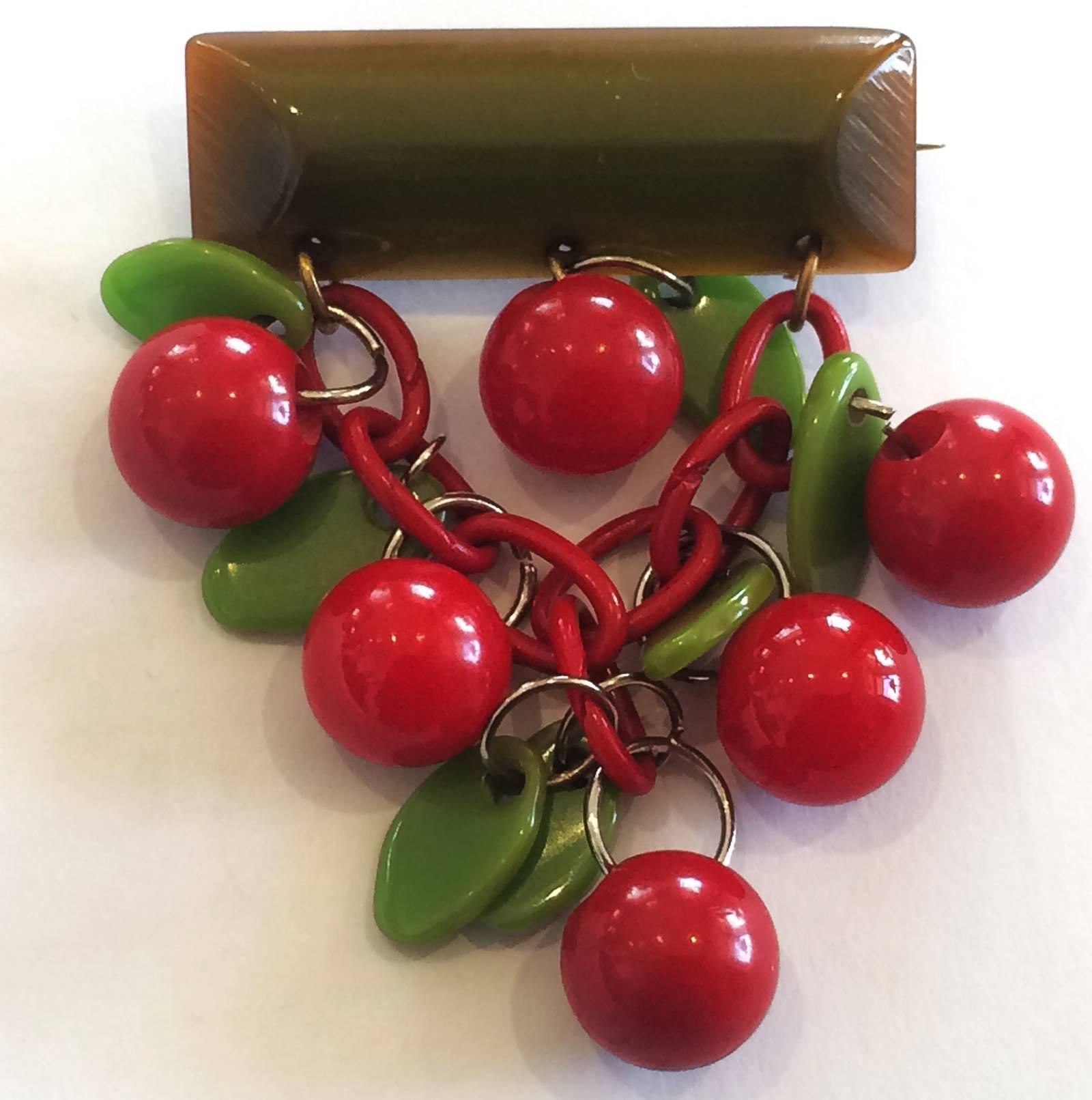 Art Deco American Bar Pin / Brooch in Bakelite, with bright Red Cherries and Green Leaves, with original “roll-over” safety pin clasp to rear. All perfect with no damage, repairs or losses. Dimensions approx..: 4.5cm wide bar  x 6.6cm drop, Cherries