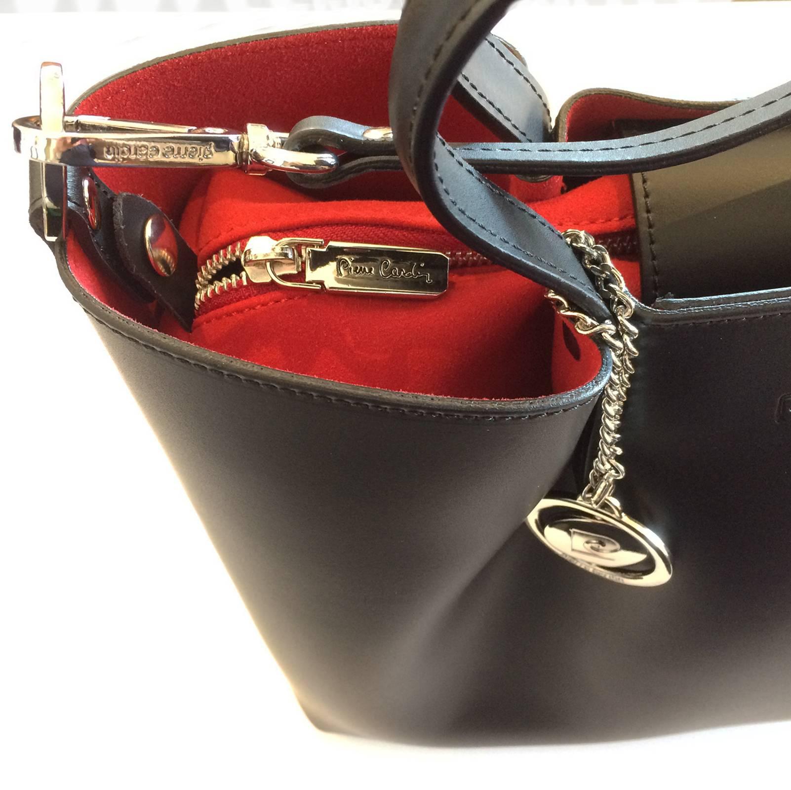 Pierre Cardin Handbag, New Old Stock, in smooth black Leather with Red Lining, all in totally New condition with original factory tags, seals, etc.. The bag has dual, half circle  hand straps, plus a detachable, long shoulder strap, all with the