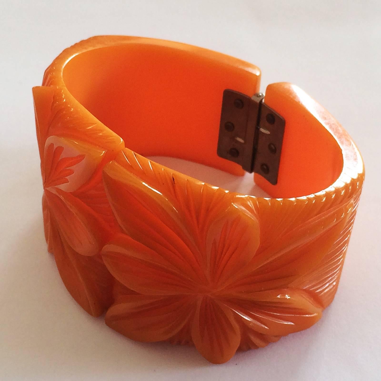Art Deco Clamper Bangle heavily carved, desirable and Rare Solid Orange Bakelite with a deeply carved Flower to each side of the front. Original nickel plate, rivetted pin, spring hinge in perfect working condition, with no damage, no repairs at all