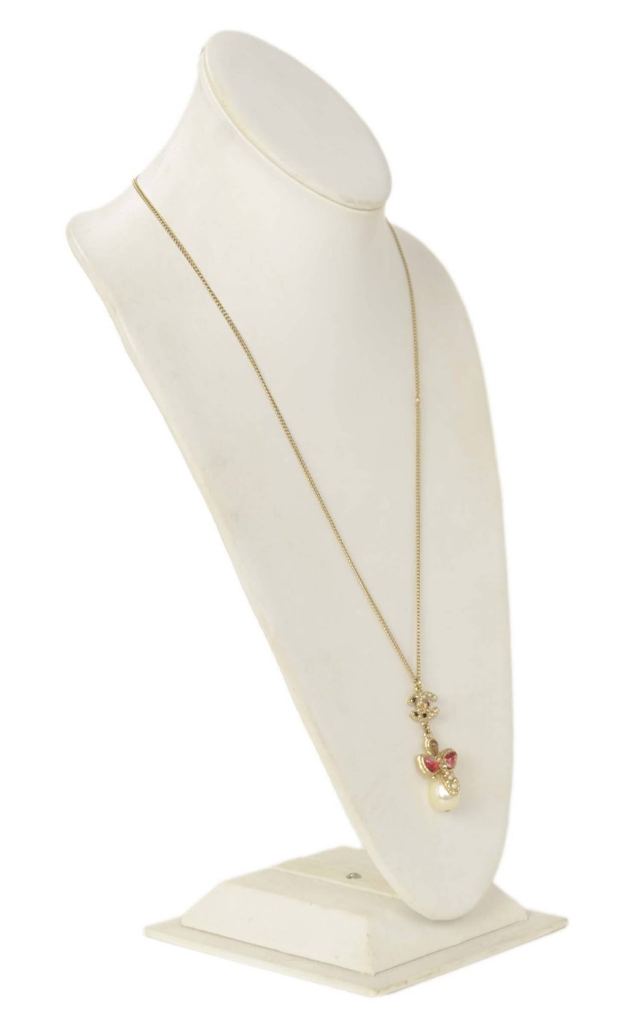 Features CC with pearls, black and burgundy enamel and a small rhinestone. Flower style pendant with red and taupe glass and faux pear tear drop. Necklace has two hooks allowing the owner to wear it shorter or longer.

-Made in: Italy
-Year of