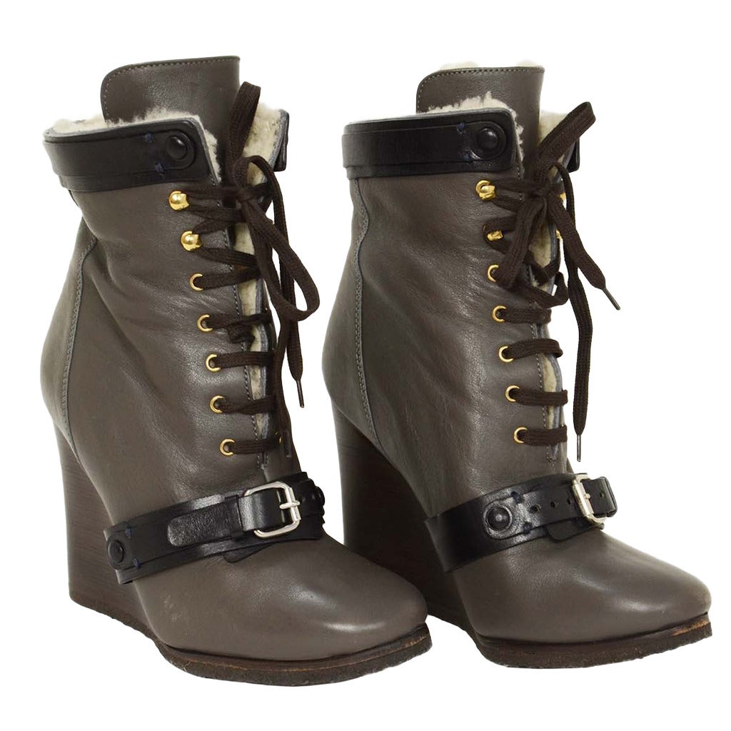 Chloe Grey Leather Shearling Wedge Lace-Up Ankle Bootie
Features black leather strap and goldtone hardware

Made in: Italy
Color: Grey w/ dark brown wedge heel, cream shearling lining and back trim
Composition: Leather and shearling
Sole Stamp: MADE