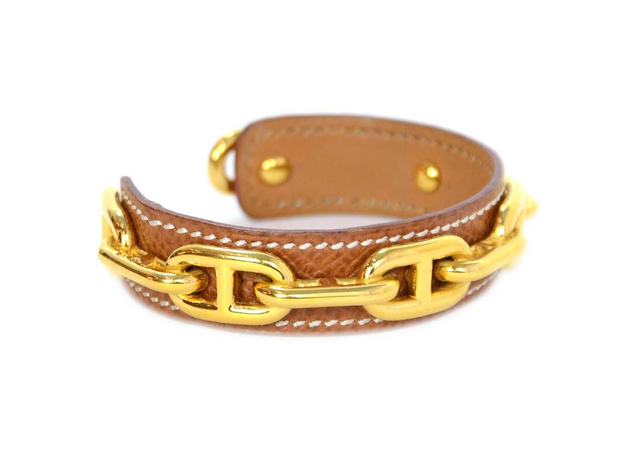 Hermes Tan Leather Cuff W/Goldtone Chaine D'ancre Links
Made in: France
Stamp: HERMES. MADE IN FRANCE
Closure: Slips on over writs
Color: Tan and Gold
Materials: Epsom leather and goldtone metal
Overall Condition: Excellent pre-owned