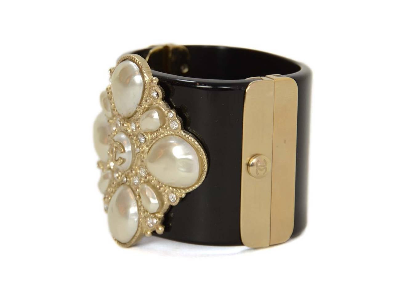 CHANEL Black Resin Clamper Cuff W/ Pearl & Rhinestone Detail

    Made in: Italy
    Year of Production: 2012
    Stamp: CHANEL B12 C MADE IN ITALY
    Closure: Clamps closed and secures with a push lock
    Color: Black with gold and pearl
 