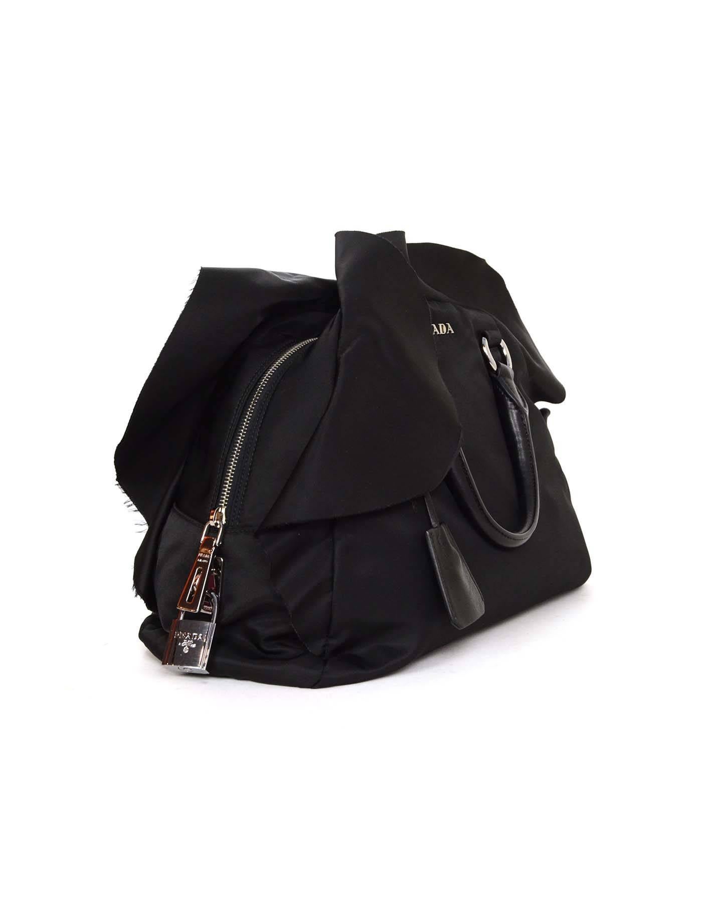 Prada Black Nylon Ruffle Bowler
Features Prada logo with detachable clochette and lock. Ruffle surrounds exterior edge on front and back of bag.

-Made In: Italy
-Color: Black
-Hardware: Silvertone
-Materials: Nylon with leather