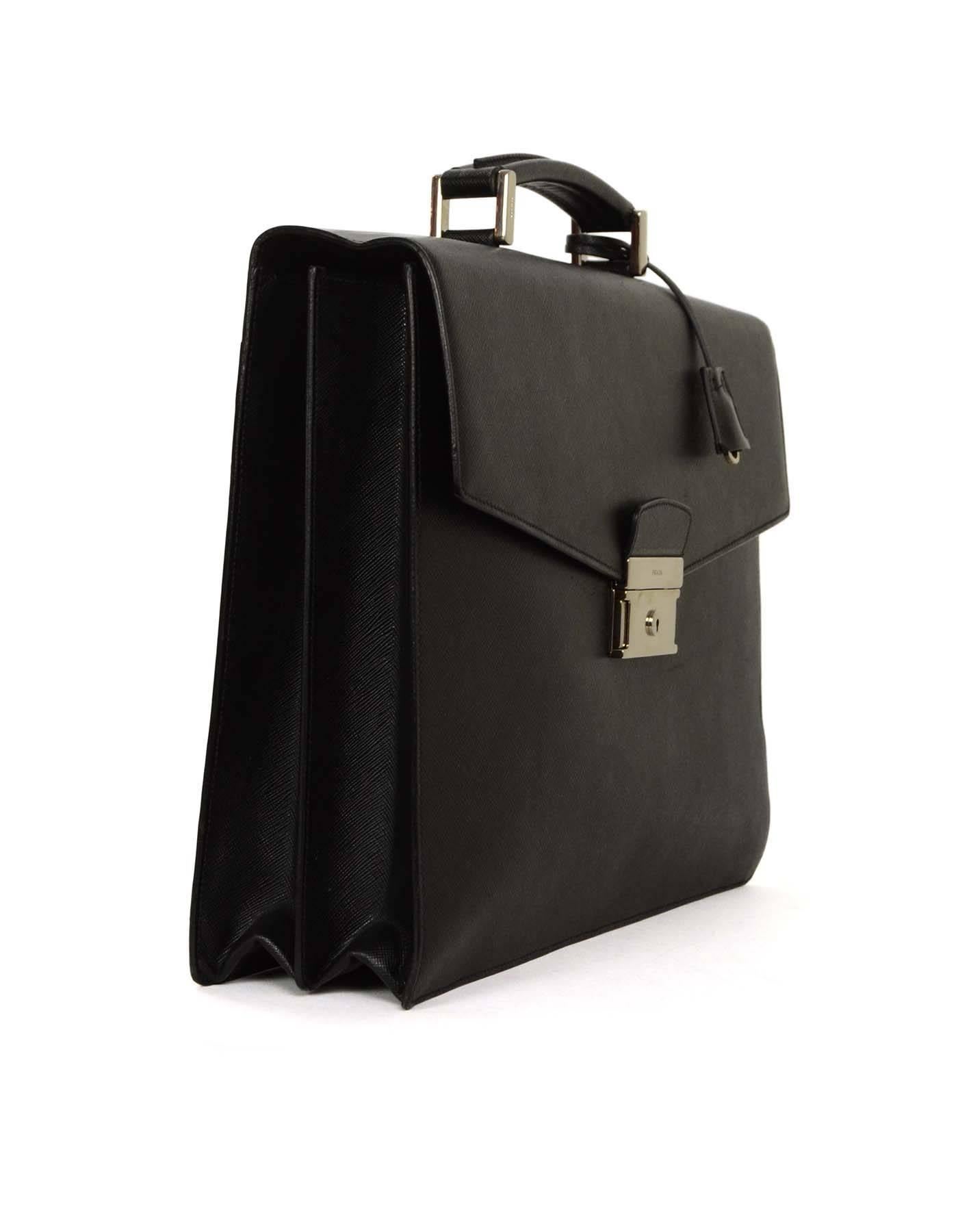 Prada Black Saffiano Briefcase 
Features Prada logo

Made In: Italy
Color: Black
Hardware: Silvertone
Materials: Saffiano leather
Lining: Black leather
Closure/Opening: Flap top with skeleton key hole push lock closure
Exterior Pockets: One