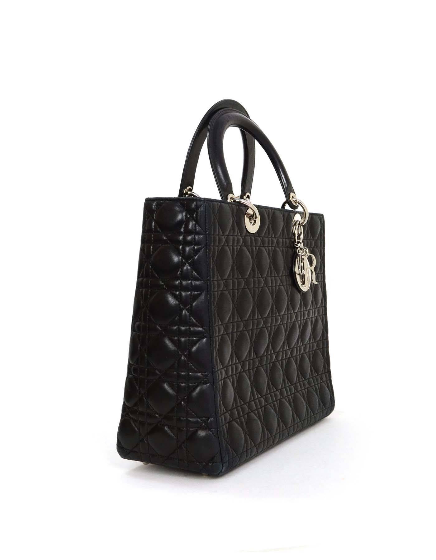 Christian Dior Black Large Lady Dior Tote 
Features optional shoulder/crossbody strap and the Christian Dior charms at handle
Made In: Italy
Color: Black
Hardware: Silvertone
Materials: Leather
Lining: Red satin-blend textile
Closure/Opening: