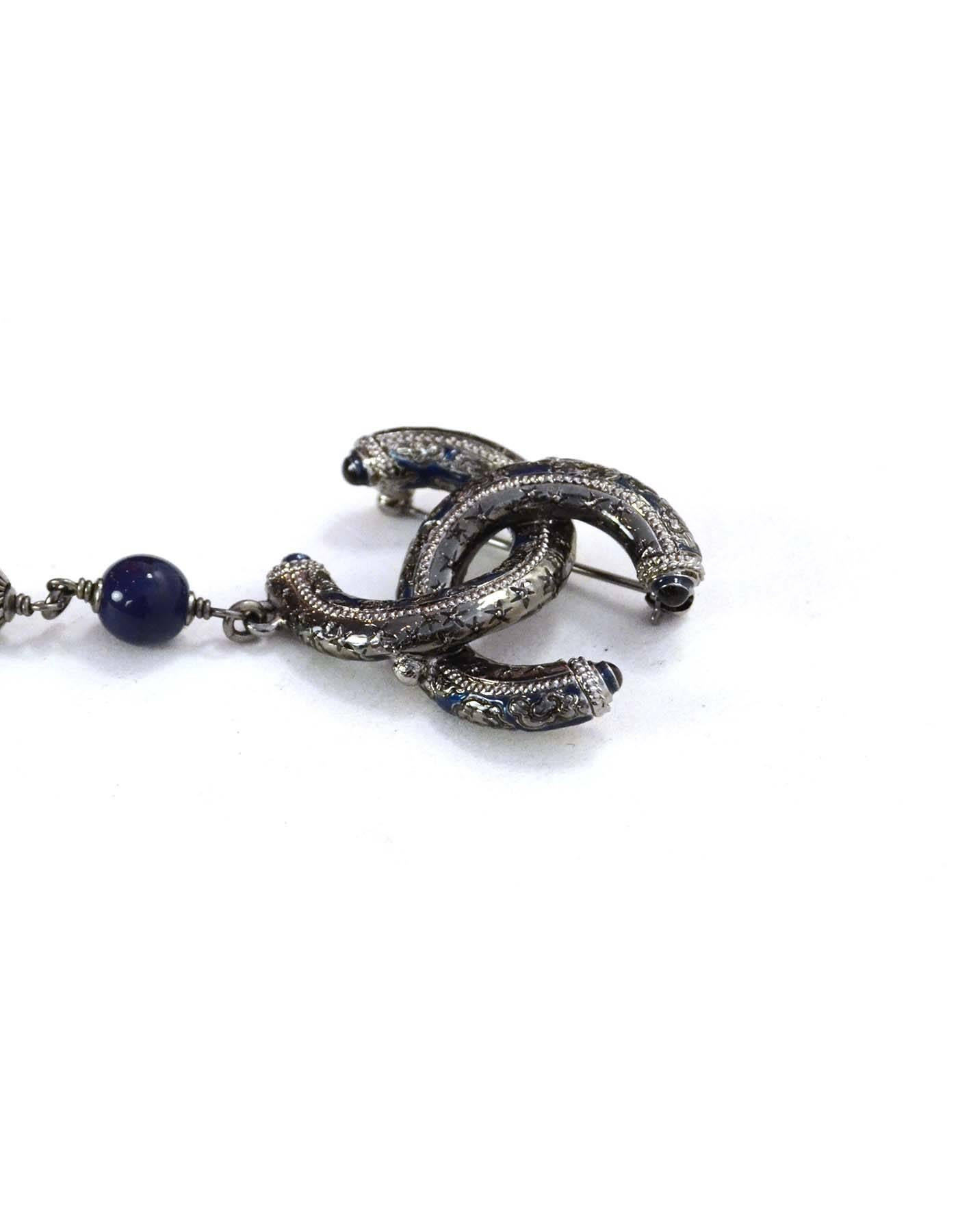 Chanel Double CC Chain Brooch
Features two CC pins with metal and bead chain in between

    Made In: France
    Year of Production: 2010
    Color: Gunmetal and blue
    Materials: Metal and beads
    Closure: Double pin back closure
   