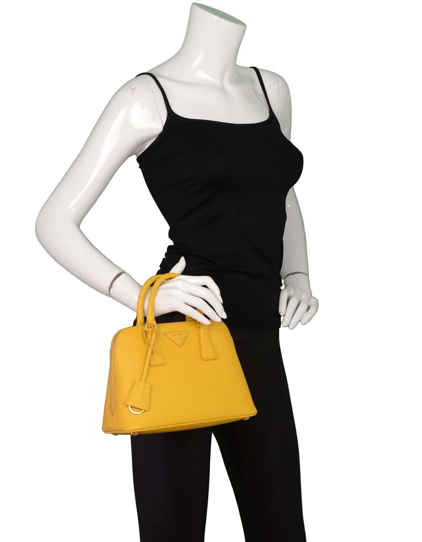 Prada Yellow Mini Promenade Saffiano Bag with GHW
Features optional shoulder strap

Made in: Italy
Color: Yellow
Hardware: Goldtone
Materials: Saffiano leather
Lining: Yellow textile
Closure/opening: Zip top
Exterior Pockets: None
Interior