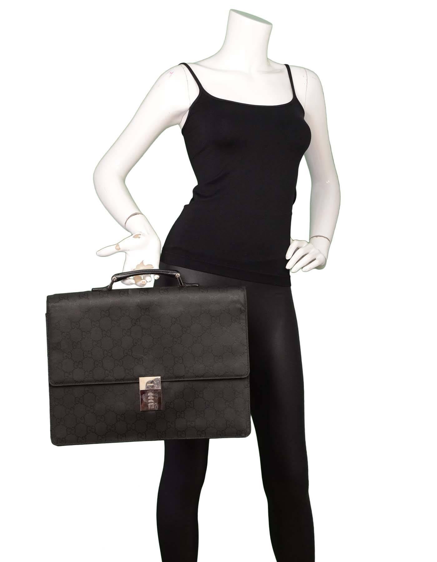 Gucci Black Monogram Canvas Attache
Features optional lock at front

Made In: Italy
Color: Black
Hardware: Silvertone
Materials: Canvas and leather
Lining: Black textile
Closure/Opening: Flap top with push-lock closure
Exterior Pockets: One