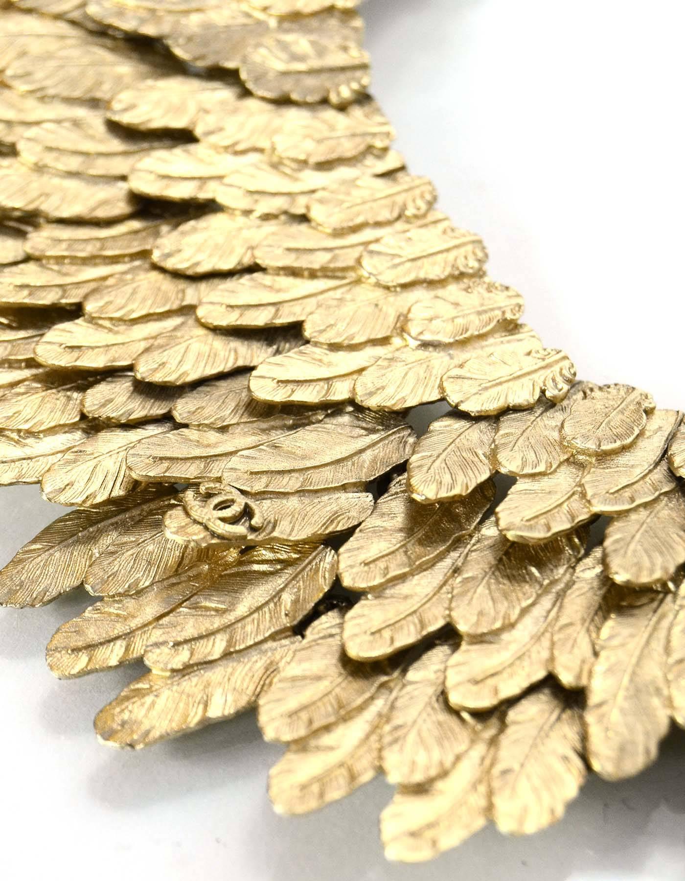 100% Authentic Chanel Goldtone Stacked Feather Collar Choker Necklace. This a-symmetrical necklace features rows of textured stacked feathers complimented with a CC on a front feather.

Made In: France
Year of Production: 2008
Color: Light