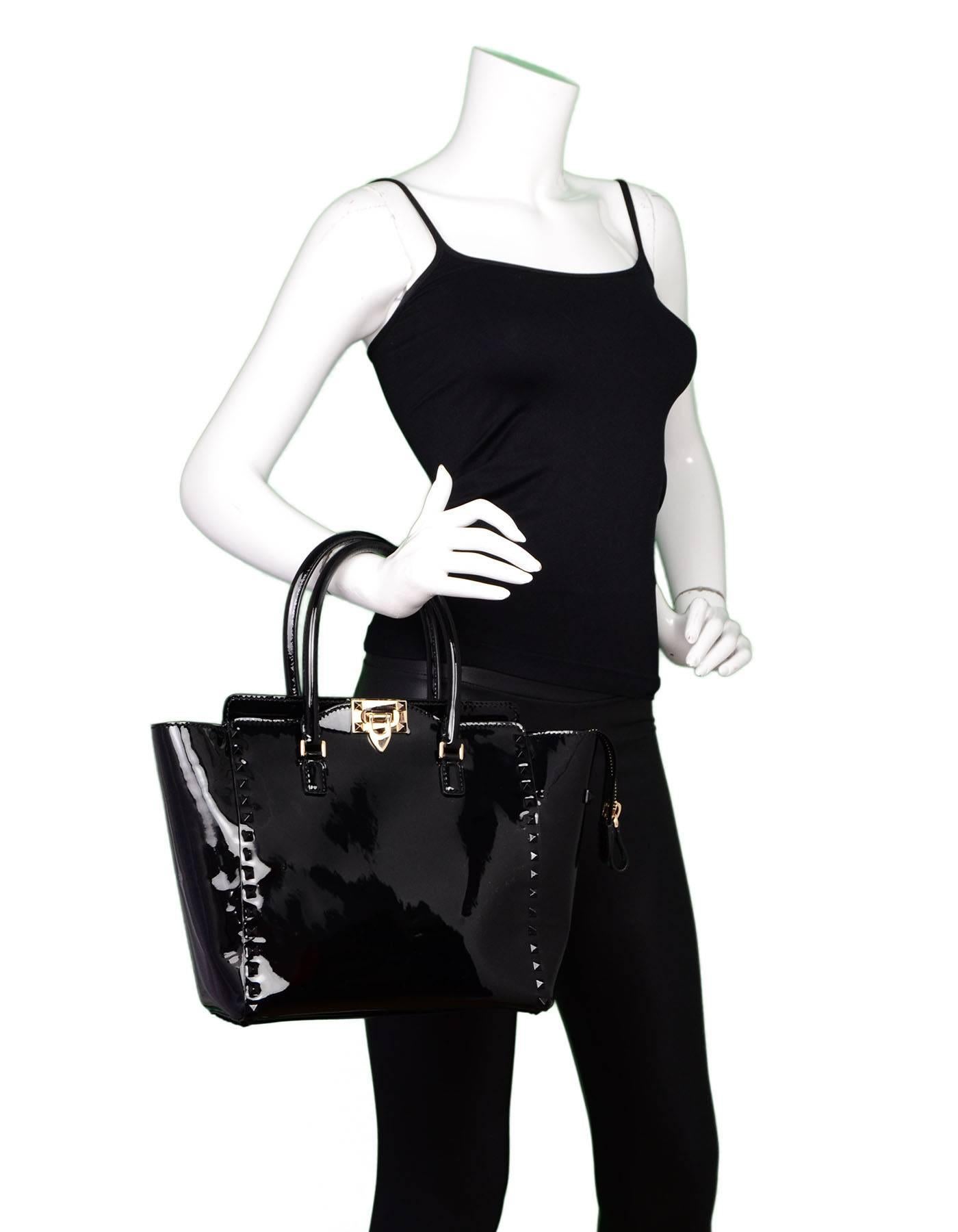 Valentino Black Patent Leather Rockstud Tote Bag
Features black studding throughout and optional shoulder strap

Made In: Italy
Color: Black
Hardware: Black, goldtone
Materials: Patent leather
Lining: Black textile
Closure/Opening: Zip top