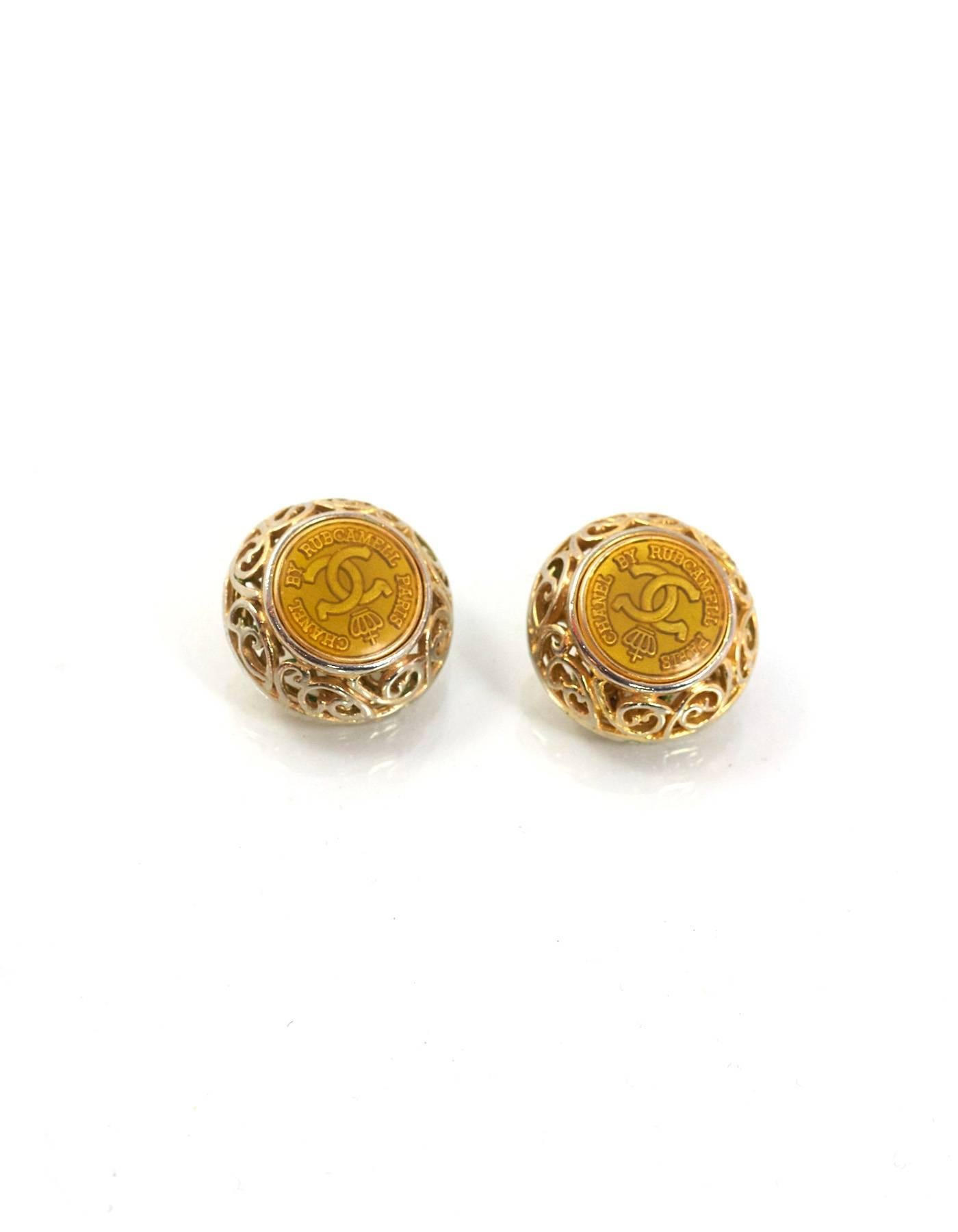 Chanel Gold Coin & Filigree Clip On Earrings
Features center CC coin

Made In: France
Year of Production: 1990-1992
Color: Goldtone
Materials: Metal
Closure/Opening: Clip on back
Stamp: Chanel CC Made in France
Overall Condition: Very good