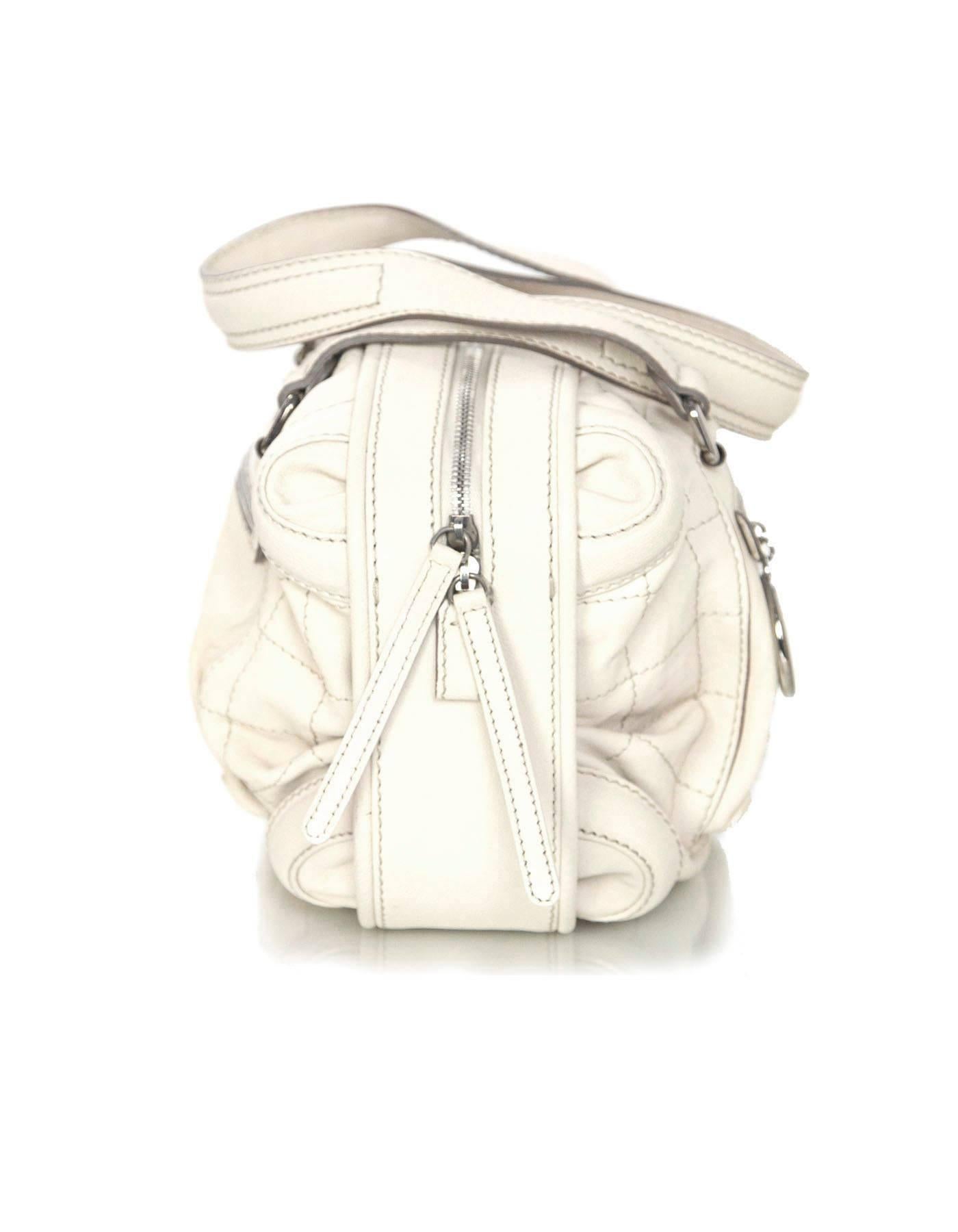 Chanel Cream Leather Bowler Bag 
Features large silvertone CC charm at front pocket zipper

Made In: Italy
Year of Production: 2006
Color: Cream
Hardware: Silvertone
Materials: Leather
Lining: Beige canvas
Closure/Opening: Zip across
