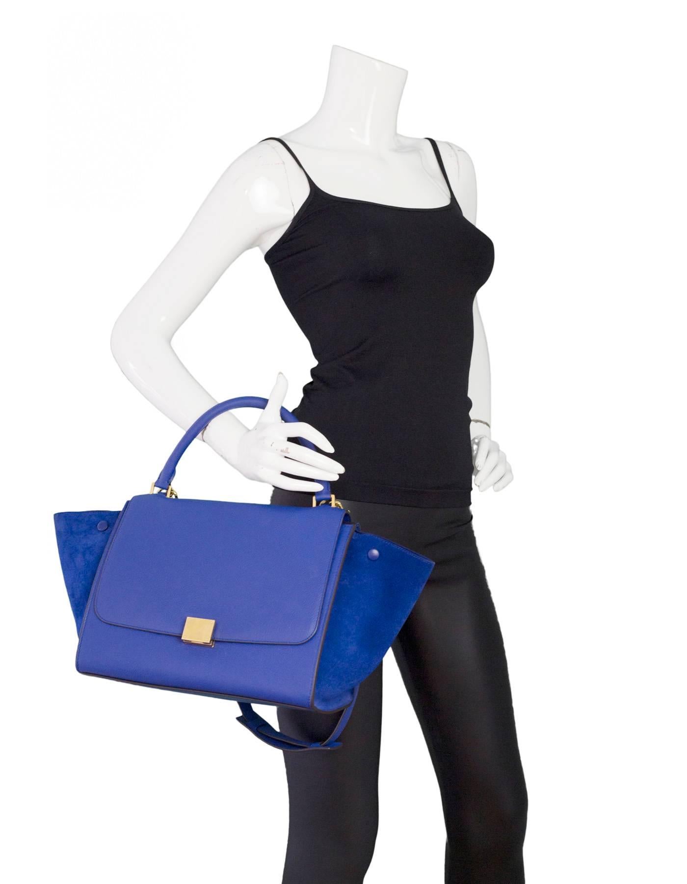 100% Authentic Celine Blue Medium Trapeze Bag. Features leather flap top with clasp closure and suede trapeze side panels. Goldtone hardware, rolled top handle, detachable shoulder strap, back zip pocket. Blue leather interior lining with two