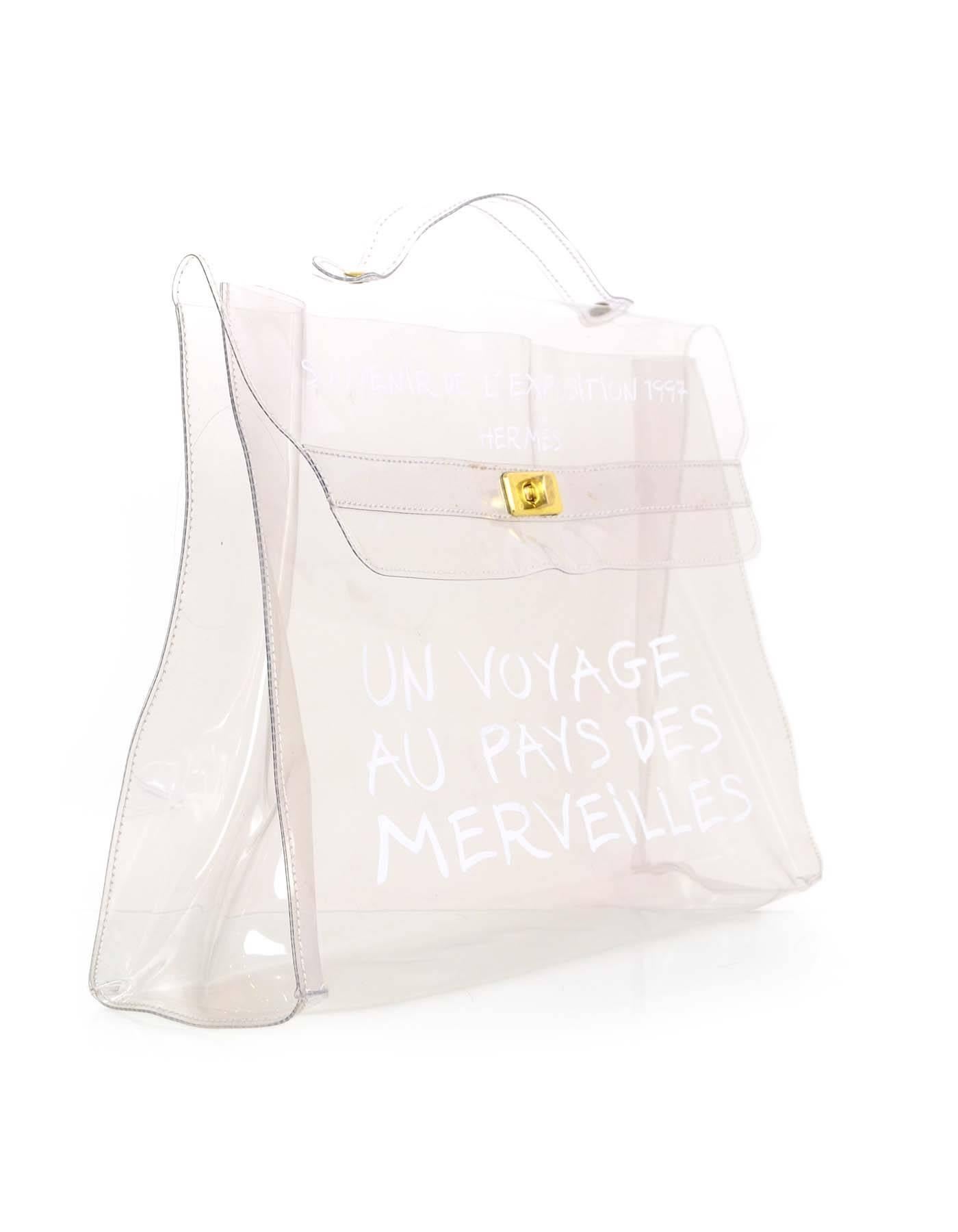Hermes Clear Plastic Un Voyage Kelly Souvenir Tote
Features white text on front of bag reading: "Souvenir De L'Exposition 1997 Hermes Un Voyage Au Pays Des Merveilles"

Made in: France
Year of Production: 1997
Color: Clear, white and