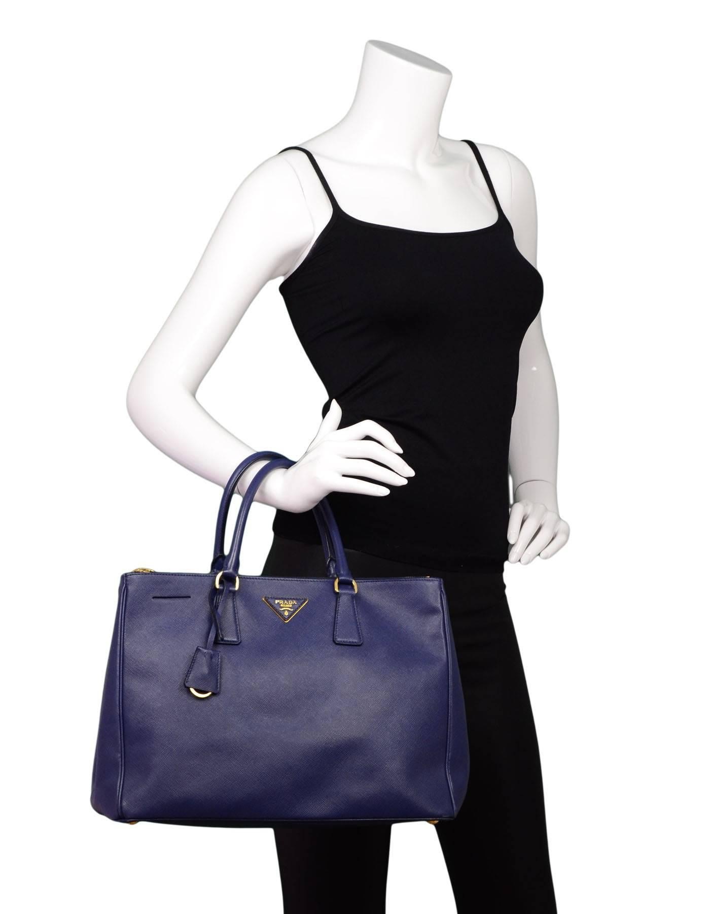 Prada Blue Saffiano Tote with GHW

Made In: Italy
Color: Blue
Hardware: Goldtone
Materials: Saffiano leather, metal
Lining: Blue textile
Closure/Opening: Open top
Exterior Pockets: None
Interior Pockets: Two zip compartments, three wall pockets, one