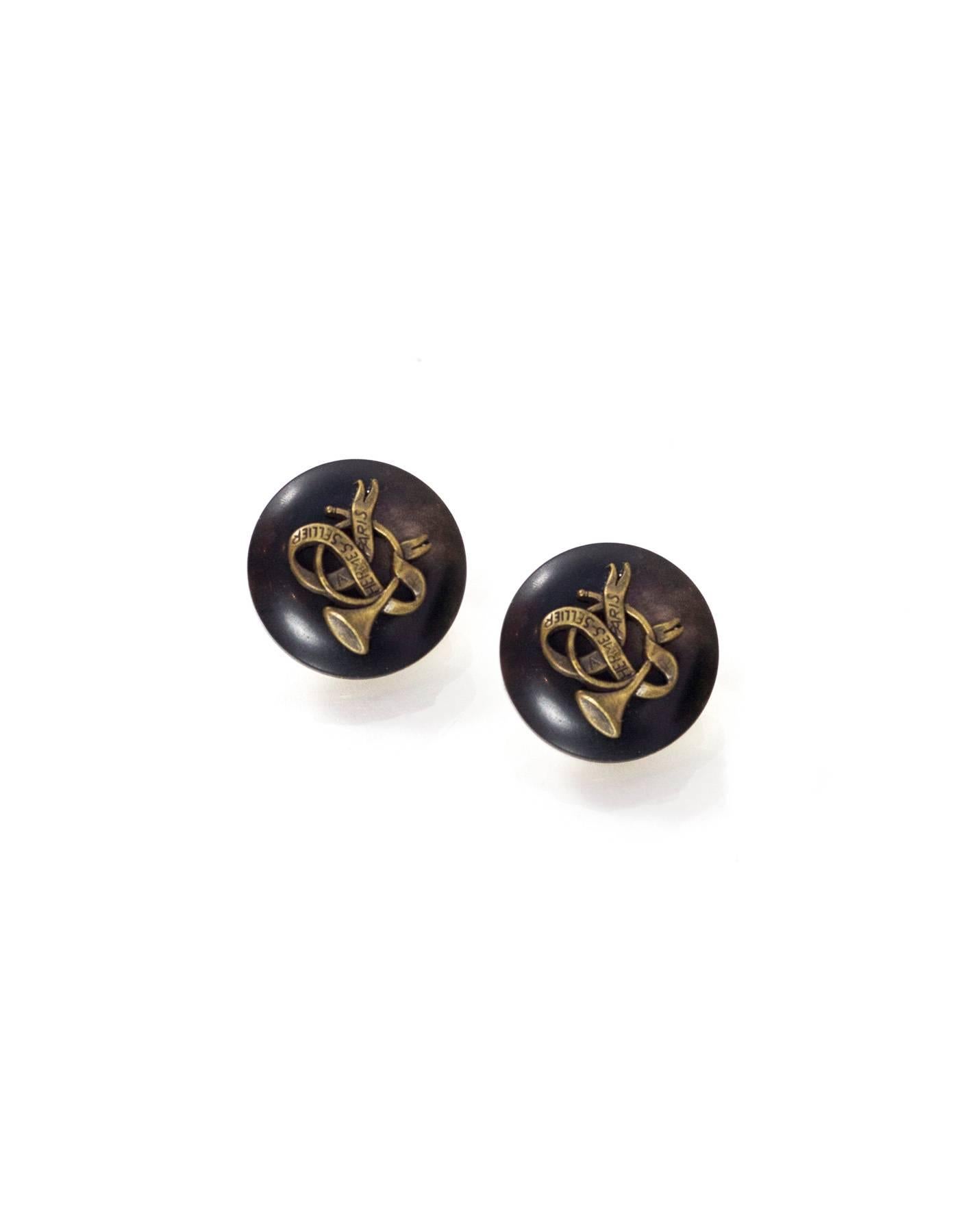 Hermes Vintage Clip-On Earrings
Features French horn motif

Color: Goldtone, brown, brass
Materials: Metal, wood
Closure: Clip on
Overall Condition: Excellent vintage, pre-owned condition with minor surface marks

Included: Hermes box
Measurements: