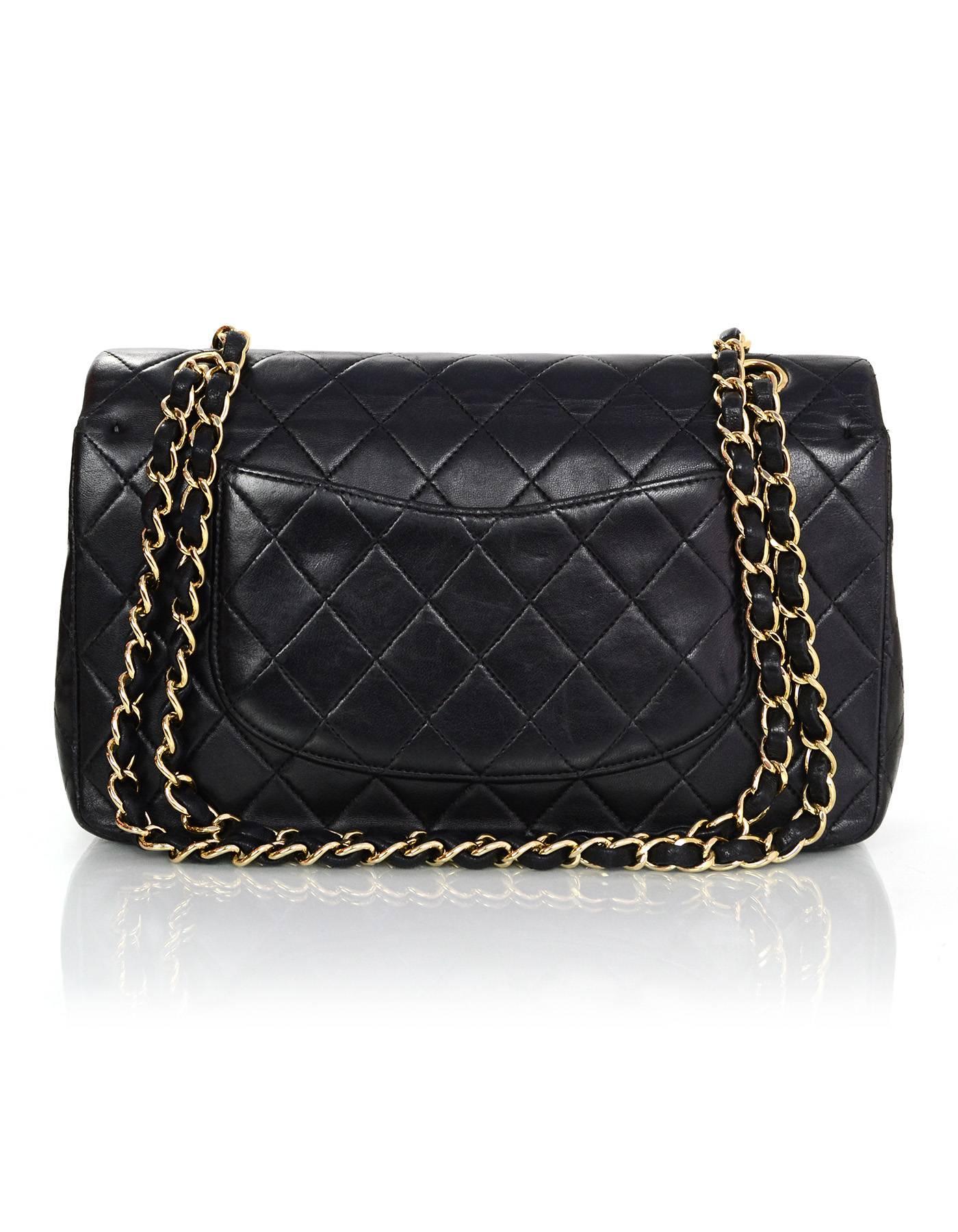 Chanel Black Quilted Classic Medium Double Flap Bag

Made In: France
Year of Production: 2002-2003
Color: Black
Hardware: Goldtone
Materials: Lambskin
Lining: Black and burgundy leather
Closure/opening: Double flap top with snap and CC twist