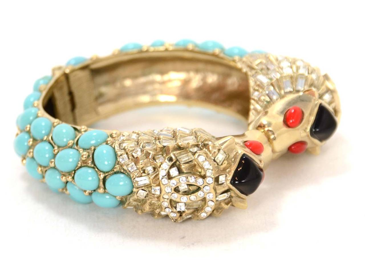 Chanel Teal & Red Stone Silver Lion's Head Cuff
Features rhinestone embellished CC's on each side

Made in: Italy
Year of Production: 2008
Stamp: 08 CC C
Closure: Hinge
Color: Teal, red, black, and silvertone
Materials: Metal and glass
Overall