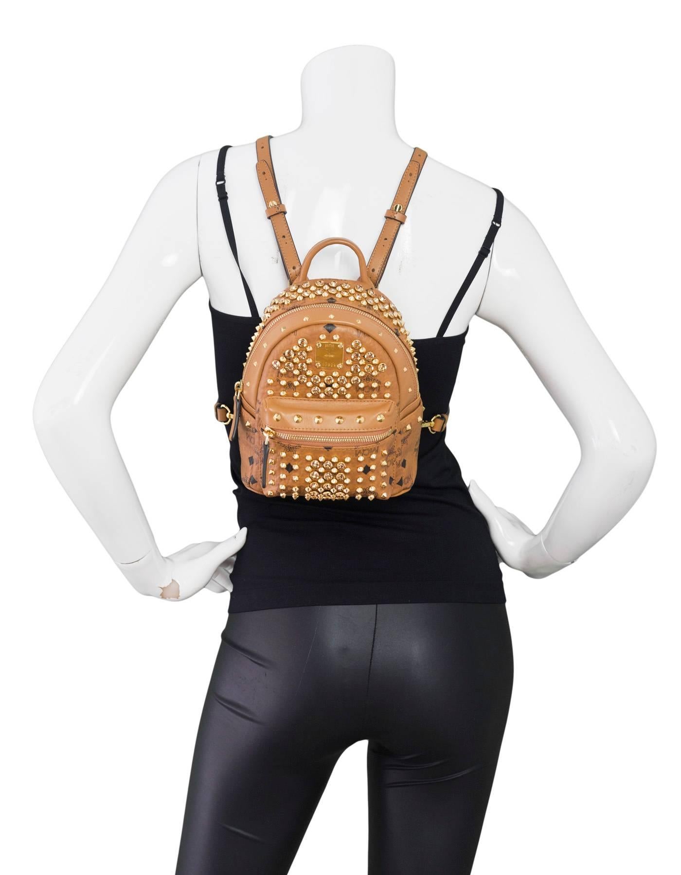 MCM Tan Monogram and Crystal Studded Mini Backpack
Features Swarovski crystals and gold studs throughout

Made In: Korea
Color: Tan, gold
Hardware: Goldtone
Materials: Leather, crystal, metal
Lining: Beige textile
Closure/Opening: Zip top
Exterior