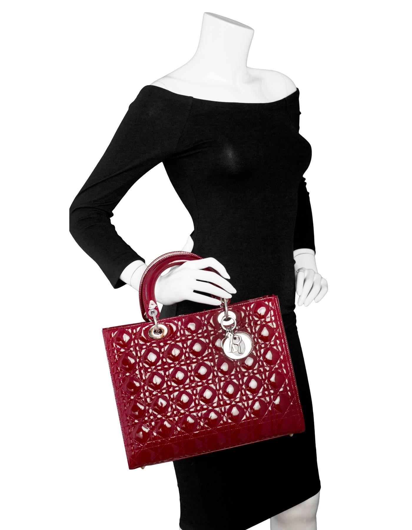 Christian Dior Red Patent Large Lady Dior Bag
Includes optional shoulder strap

Made In: Italy
Color: Red
Hardware: Silvertone
Materials: Patent leather, metal
Lining: Red textile
Closure/Opening: Zip top
Exterior Pockets: None
Interior Pockets: One