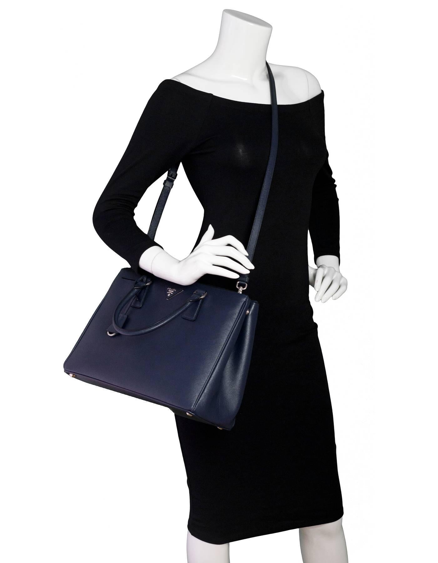 Prada Baltico Navy Medium Saffiano Leather Tote

Made In: Italy
Color: Navy
Materials: Saffiano leather, metal
Lining: Navy textile
Closure/Opening: Open top
Exterior Pockets: Zip compatments at front and back
Interior Pockets: One zip wall pocket,
