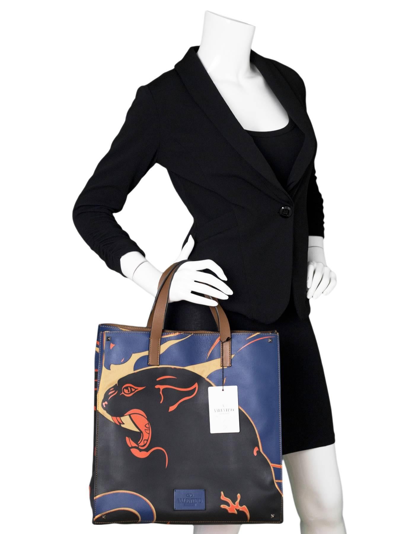 Valentino Navy Leather & Canvas Panther Print Tote

Made In: Italy
Color: Black, navy, orange
Hardware: None
Materials: Leather, canvas
Lining: Brown leather
Closure/Opening: Open top with center snap
Exterior Pockets: None
Interior Pockets: