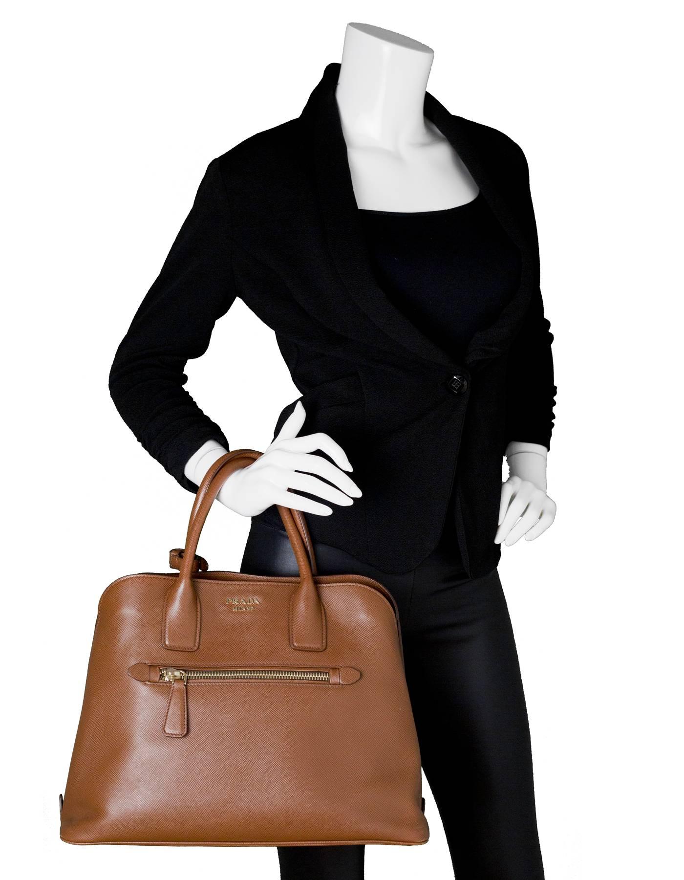 Prada Brown Saffiano Leather Palissandro Tote
Features optional shoulder strap

Made In: Italy
Color: Brown
Materials: Saffiano leather, metal
Lining: Brown leather
Closure/Opening: Open top with center snap
Exterior Pockets: Front zip