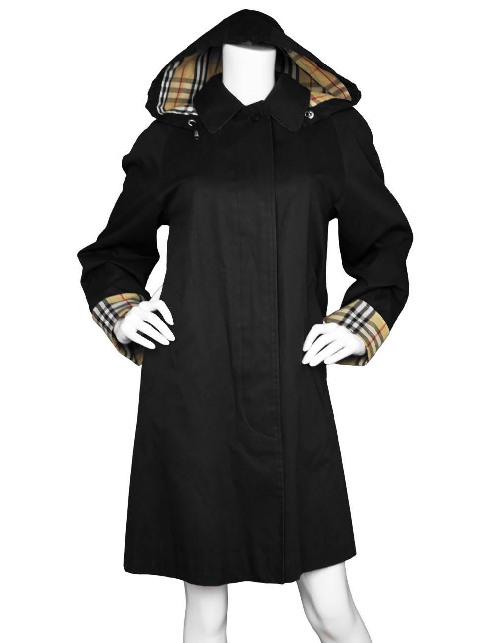 Burberry London Black Hooded Trench Coat
Features removable hood

Color: Black
Composition: 100% Cotton
Lining: Nova plaid, 50% cotton, 50% polyester
Closure/Opening: Single breasted button down front 
Exterior Pockets: Two hip pockets
Interior