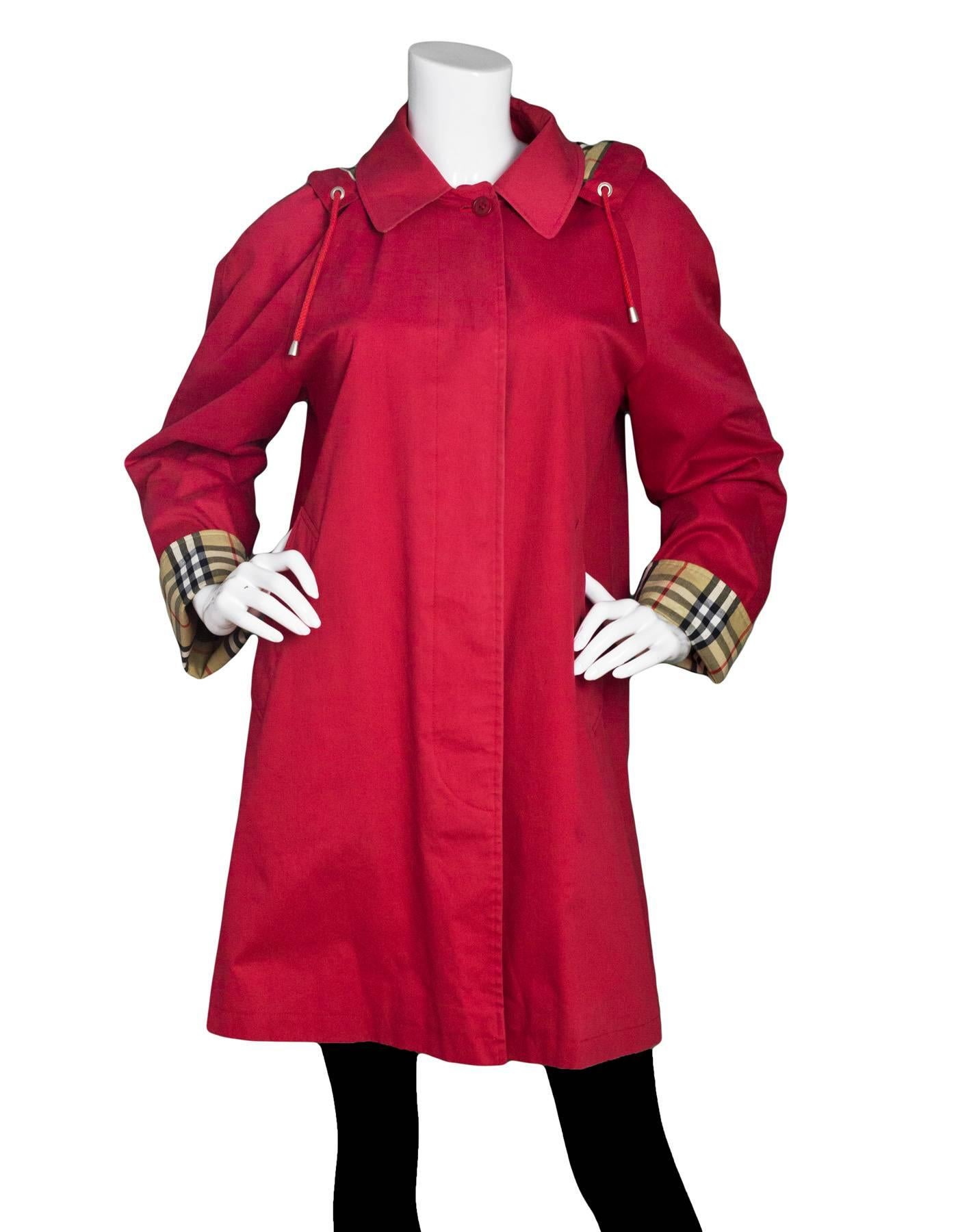 Burberry London Red Cotton Hooded Trench Coat 
Features detachable hood

Color: Red
Composition: 100% cotton
Lining: Nova plaid, 50% cotton, 50% polyester
Closure/Opening: Button down front
Exterior Pockets: Two hip pockets
Interior Pockets: