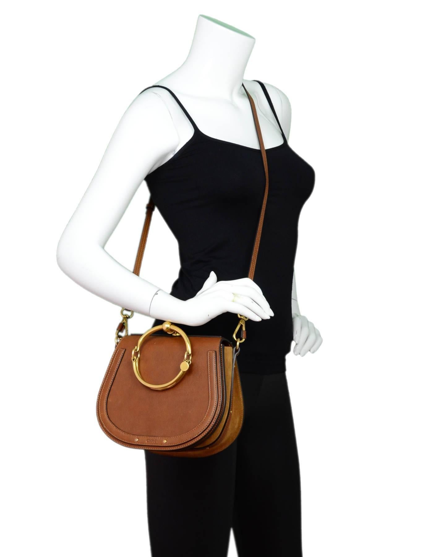 Chloe Caramel Calfskin & Suede Medium Nile Bracelet Bag

Made In: Italy
Color: Caramel
Hardware: Goldtone
Materials: Leather, suede, metal
Lining: Beige textile
Closure/opening: Flap top with snap closure
Exterior Pockets: Patch pocket at